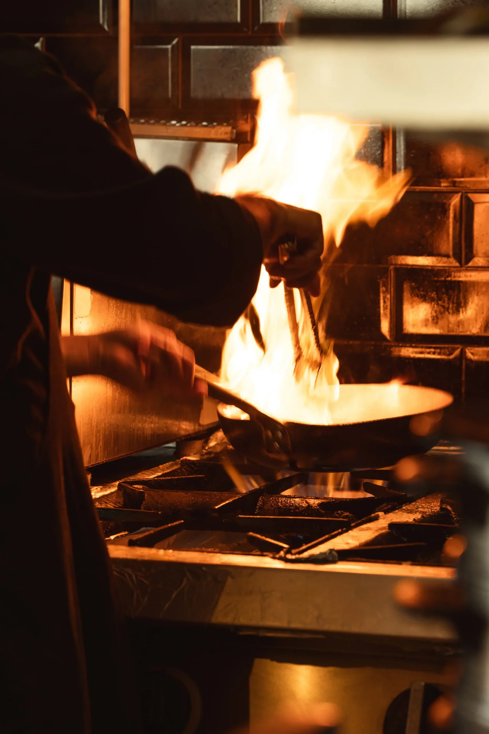 Chef cooking over open flames in a restaurant kitchen