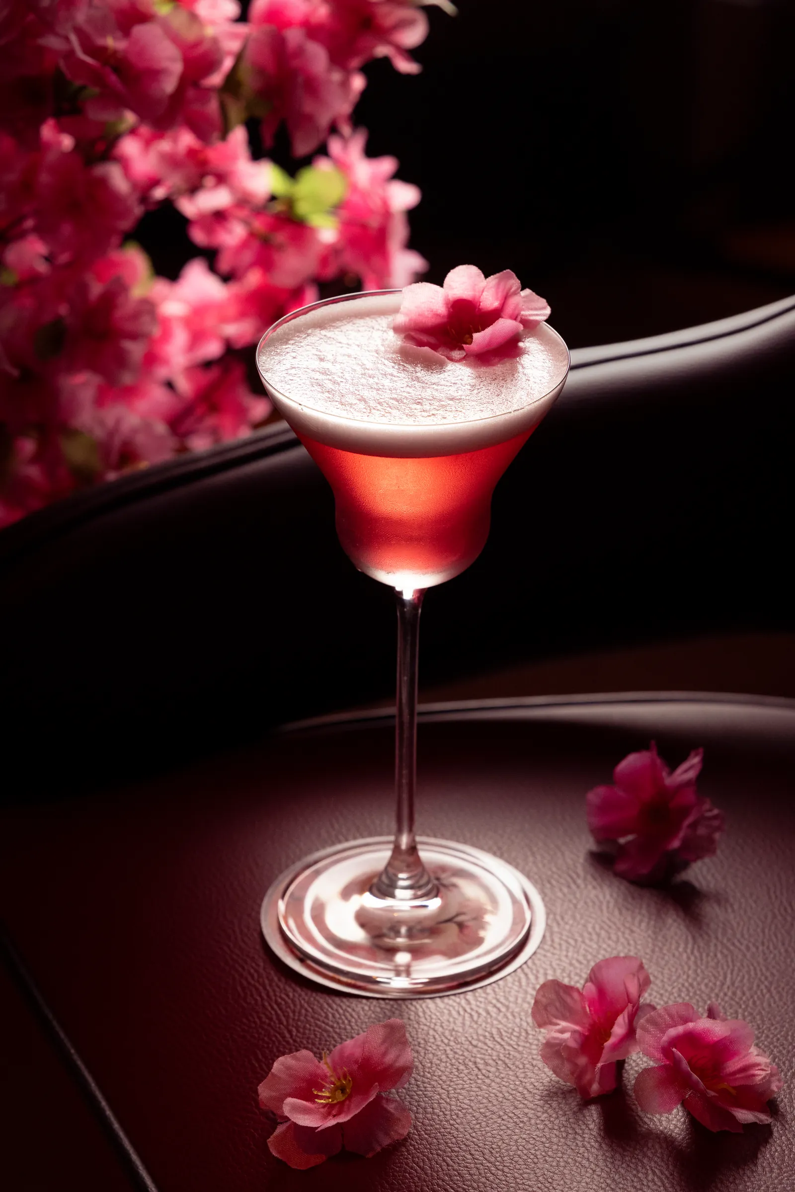 Pink cocktail in a coupe glass among blossom