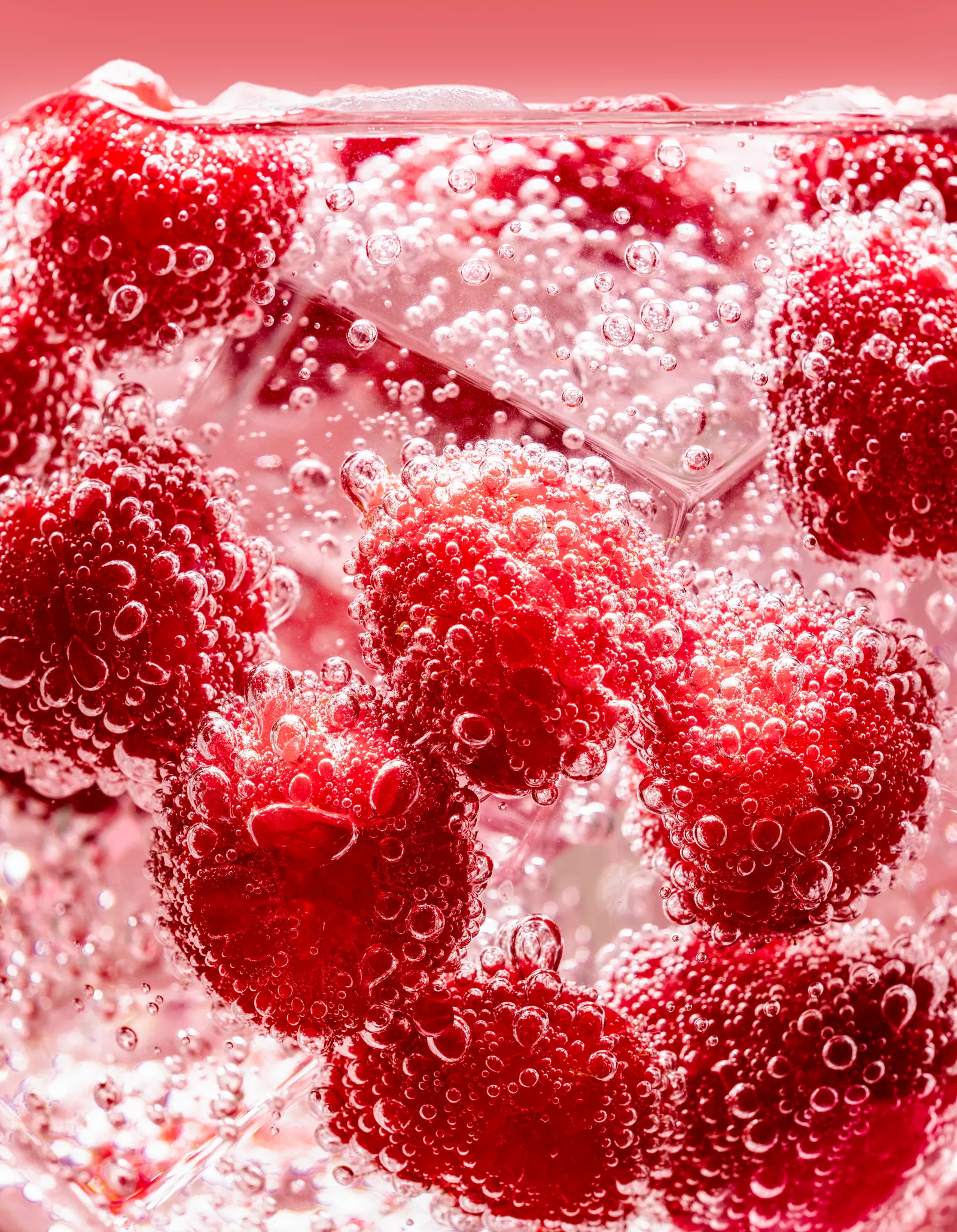 Raspberries in a sparkling pink drink with ice