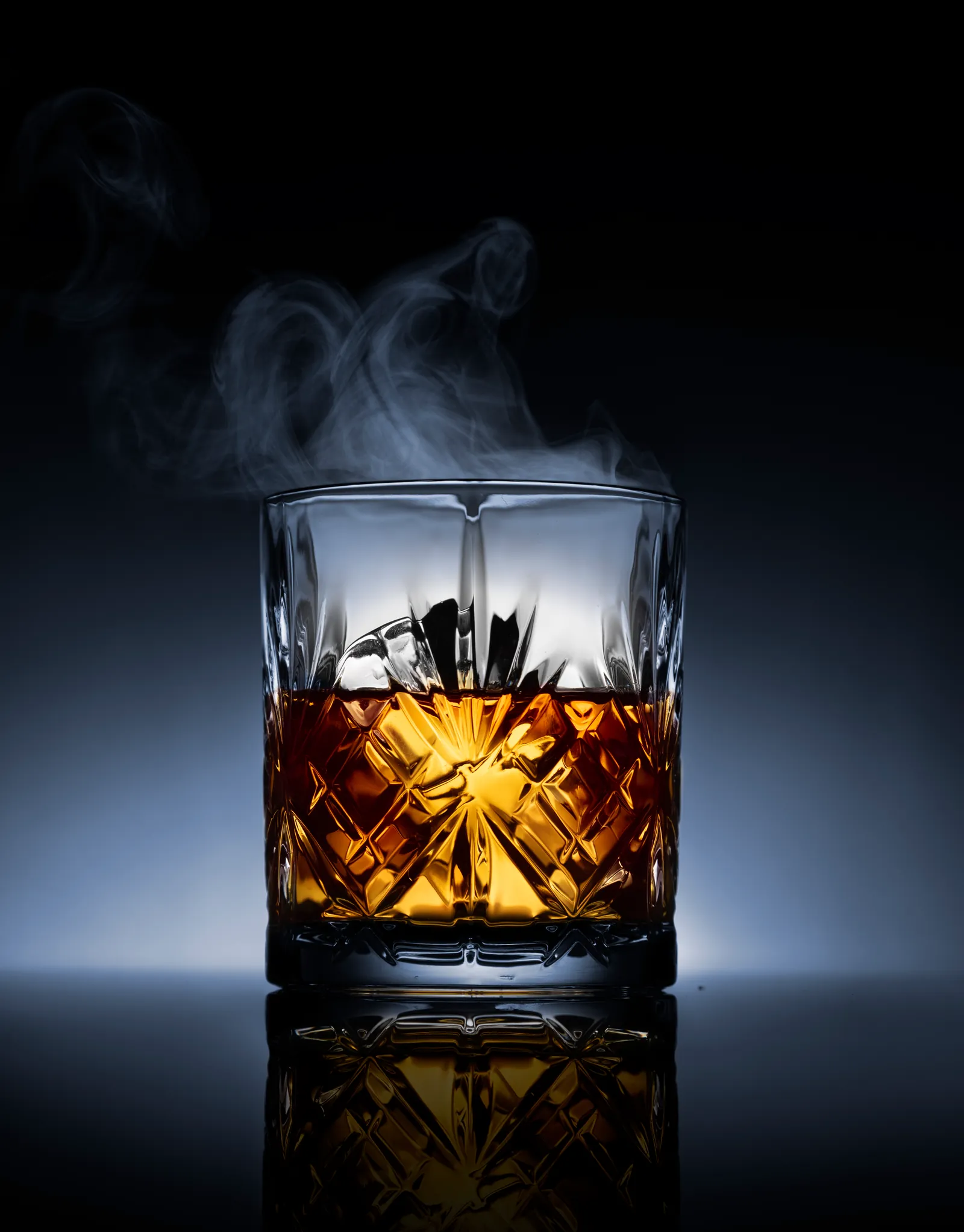 Whisky glass with a curl of smoke against black
