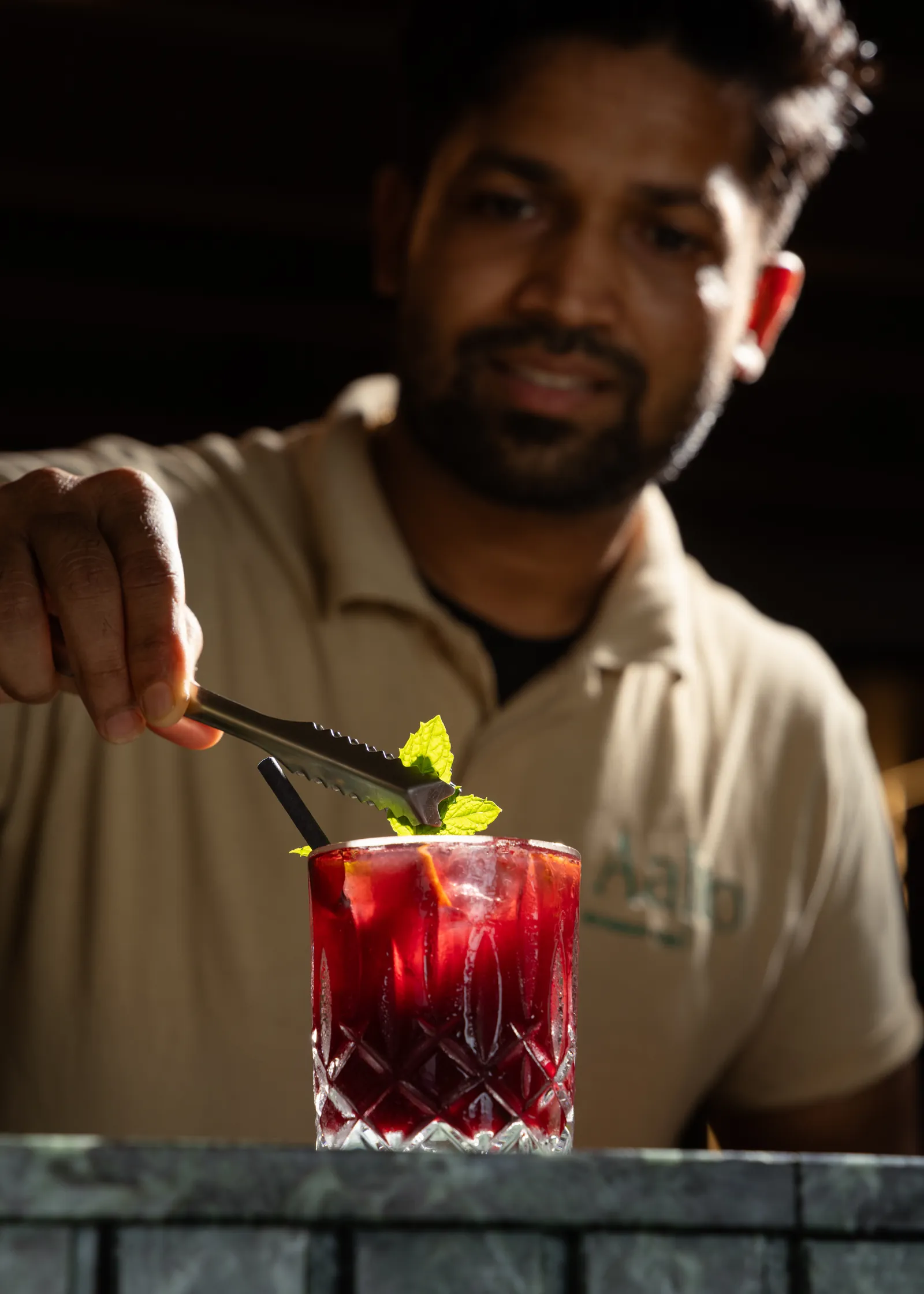 Bartender garnishing a red cocktail