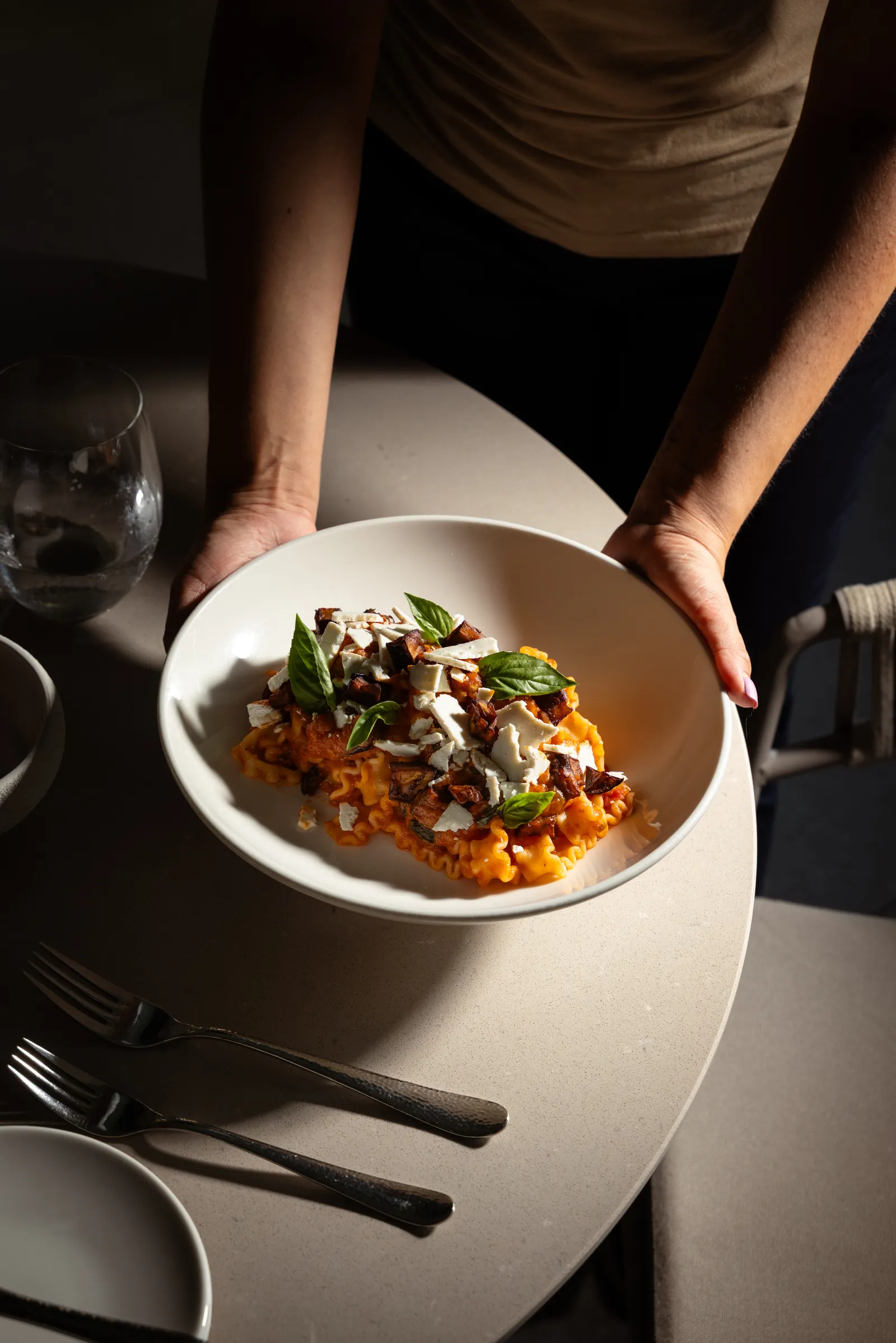 Server presenting a plated main course at the table