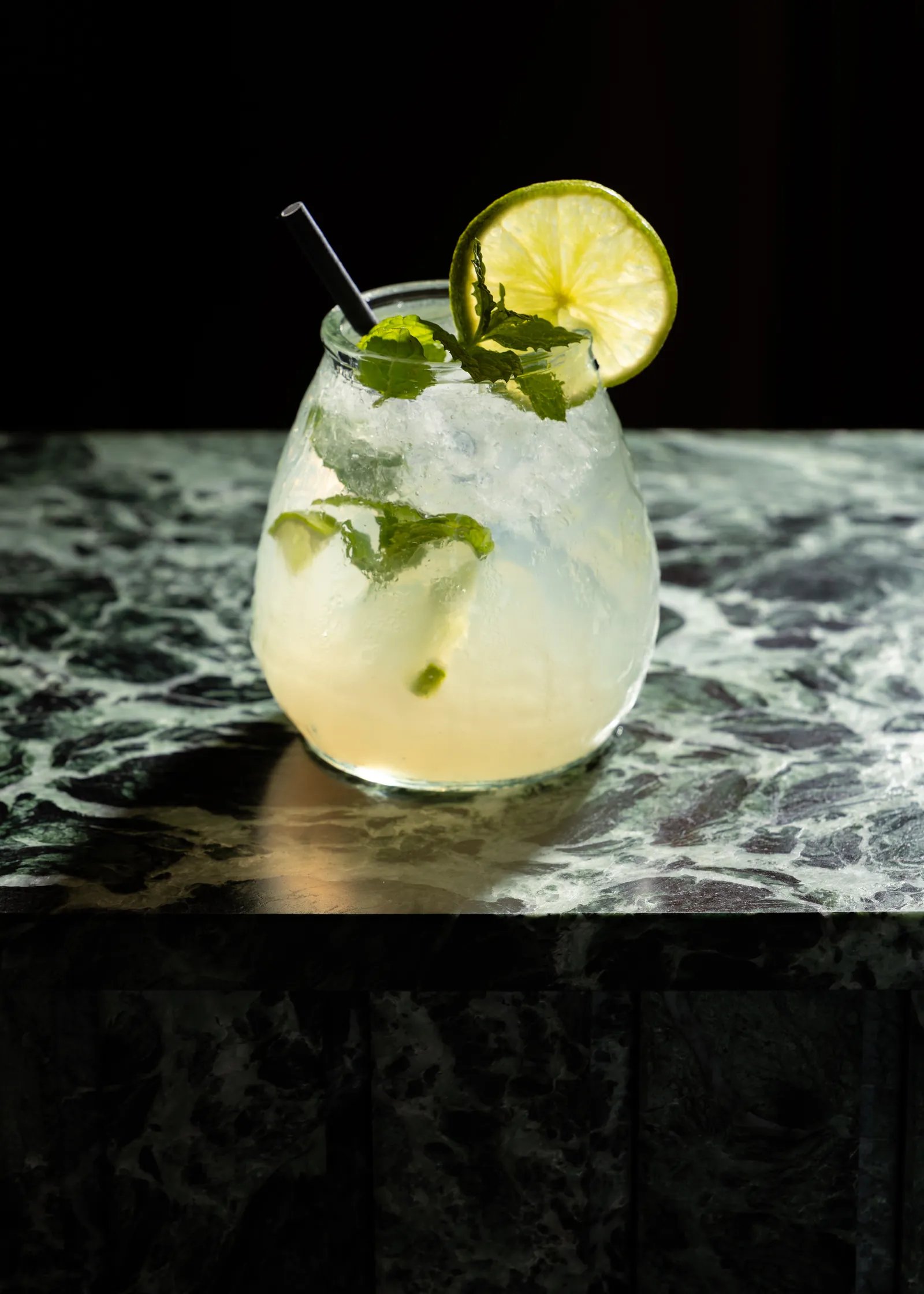 Lime and mint cocktail in a glass on a green marble surface