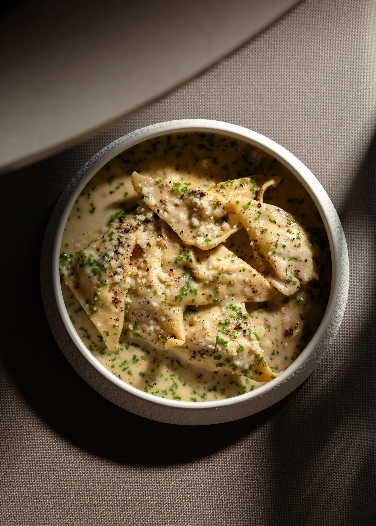 Creamy pasta with herbs in a deep bowl, seen from above