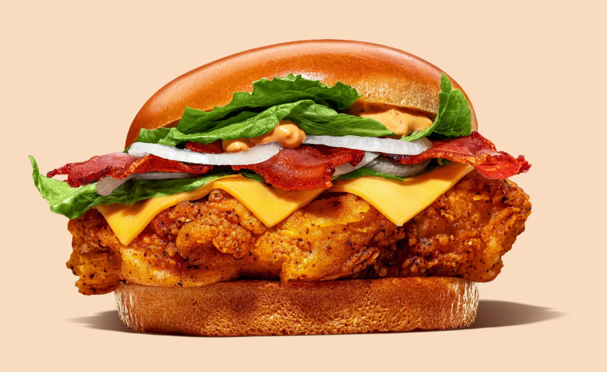 Chicken burger with bacon, melted cheese, lettuce and onion on a peach background, Chickoo, San Gwann, Malta