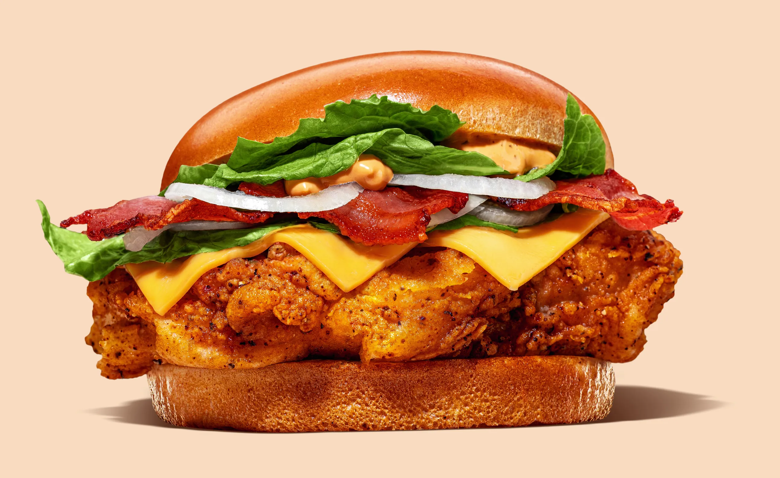 Chicken burger with bacon, melted cheese, lettuce and onion on a peach background, Chickoo, San Gwann, Malta
