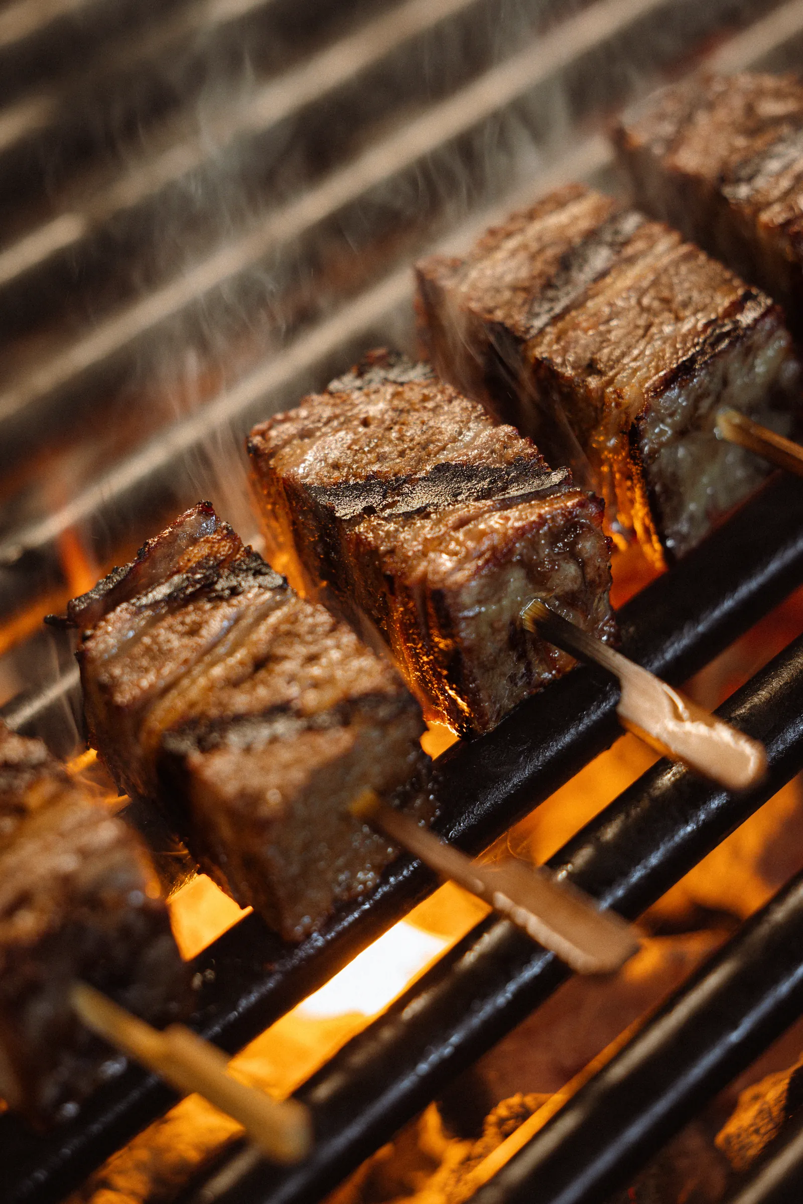Charred meat pieces grilling over flames