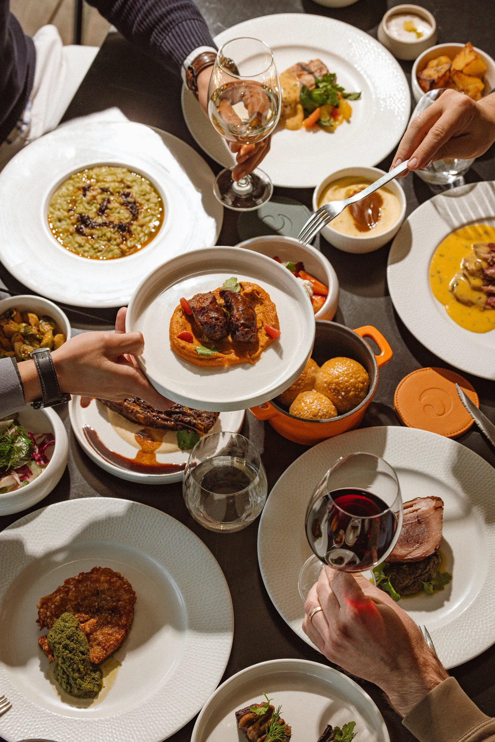 Table of shared dishes seen from above, with hands reaching in