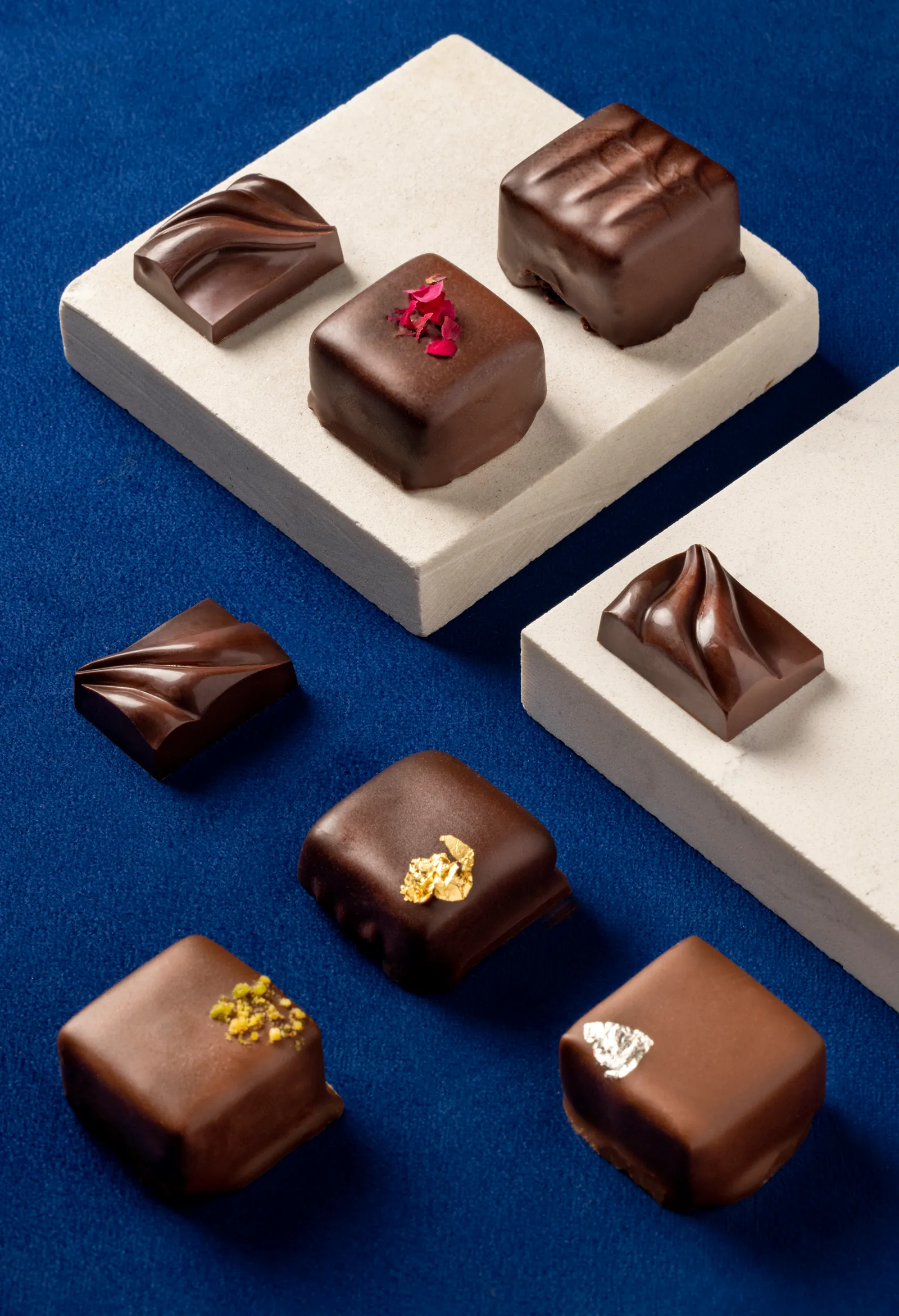 Chocolate pralines arranged on white blocks over a blue surface