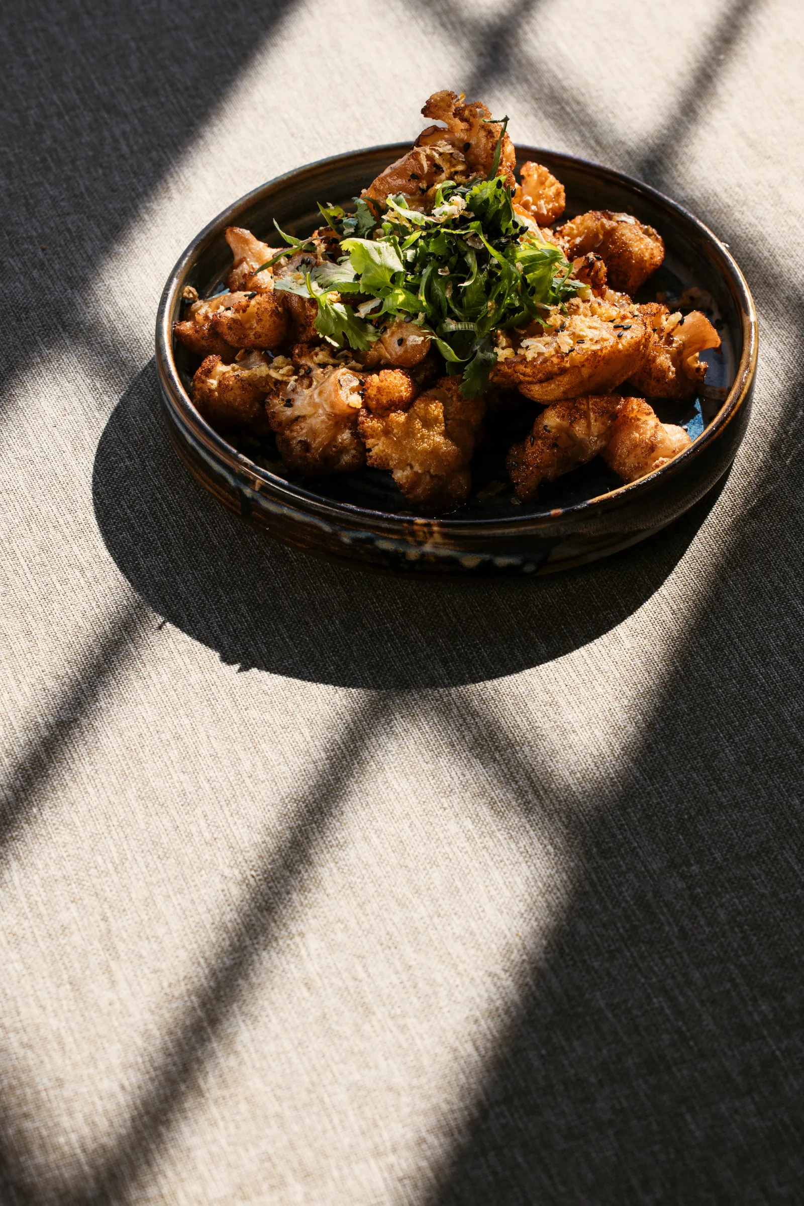 Crispy fried dish with fresh herbs in a dark bowl