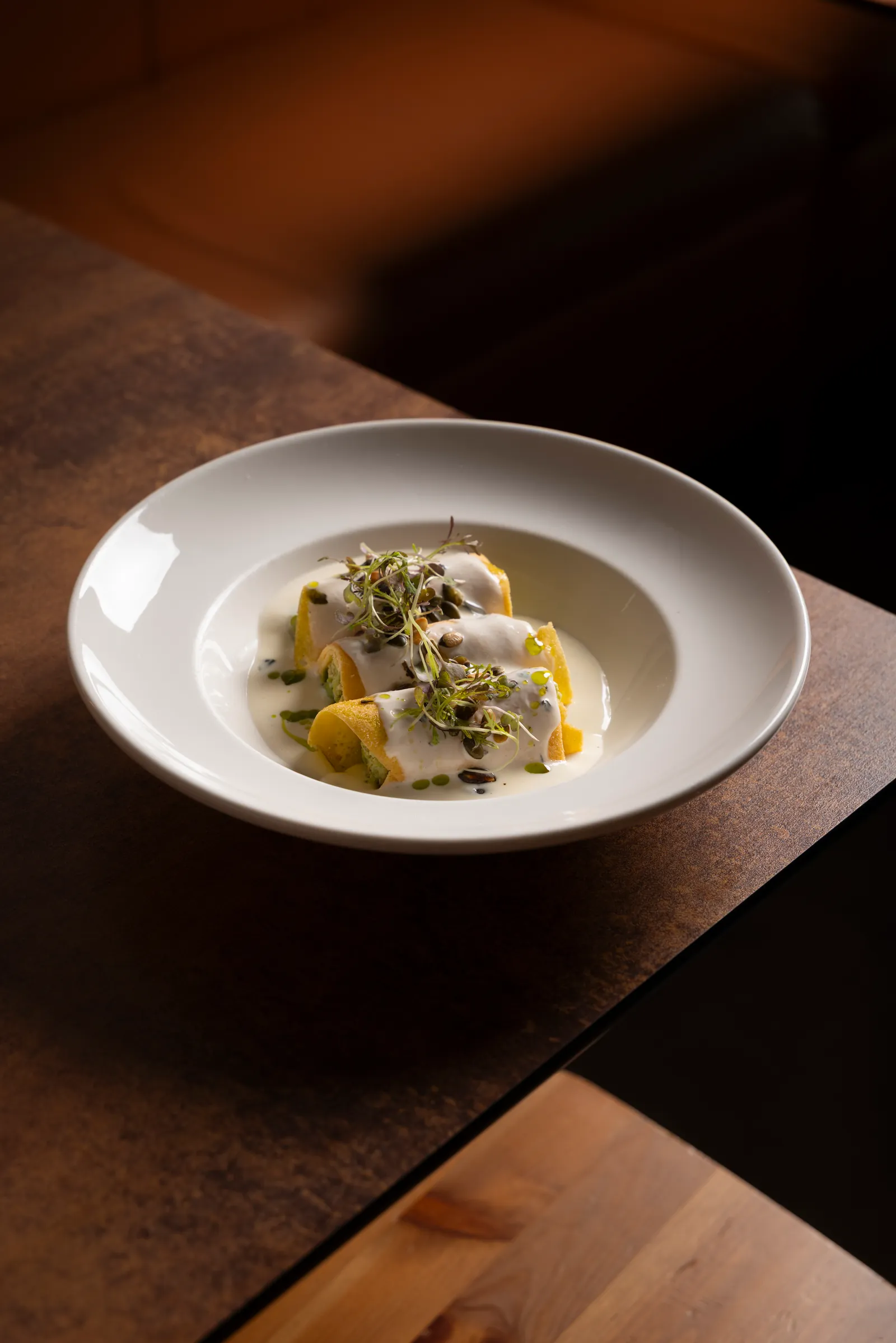 Pasta in a white bowl on a wooden table in warm light