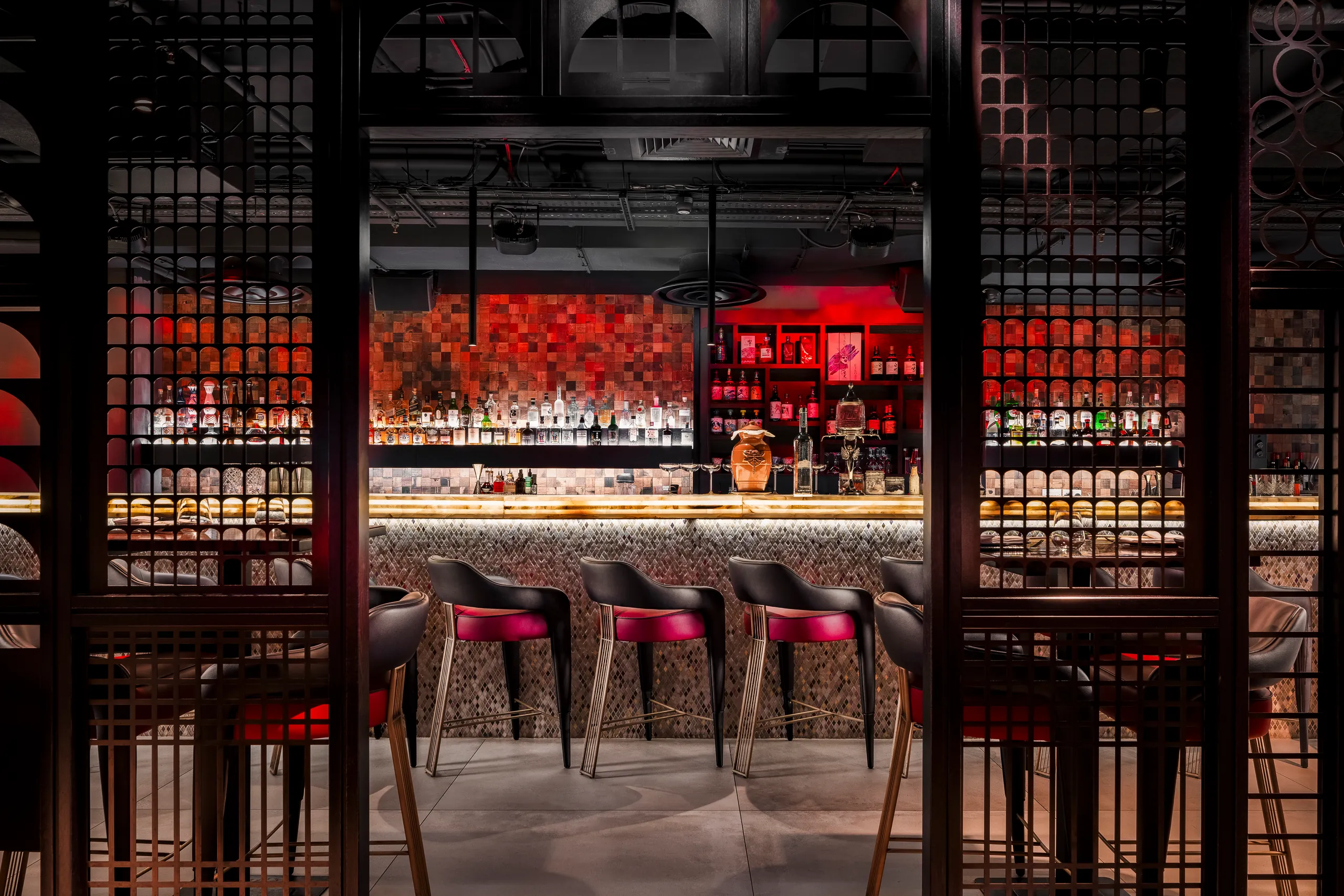 Bar with red stools and red blossoms seen through dark timber screens