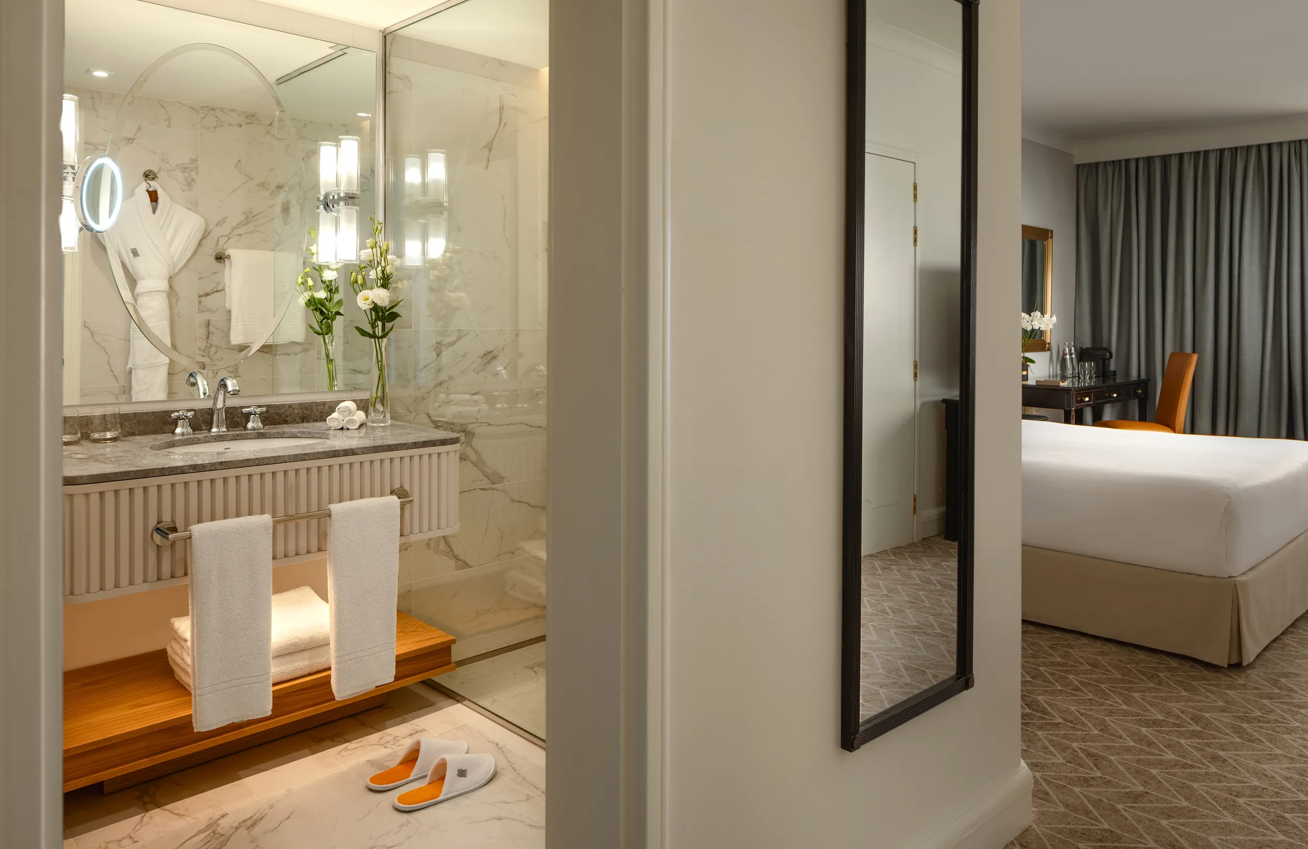 Marble bathroom vanity with robe and slippers, seen beside the bedroom at Corinthia St George's Bay