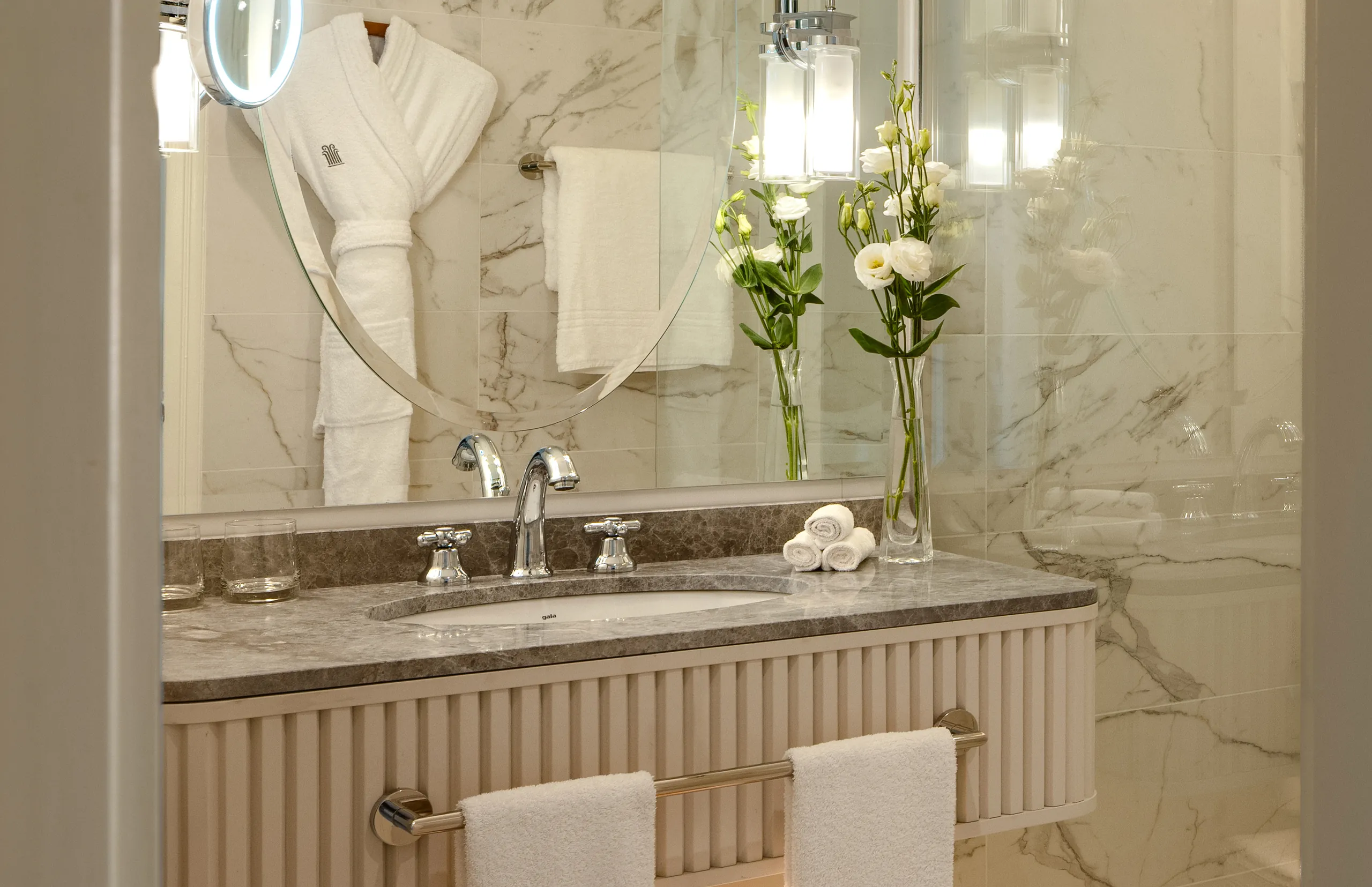 Marble bathroom vanity with fluted cabinet, towels and white flowers, Corinthia St George's Bay