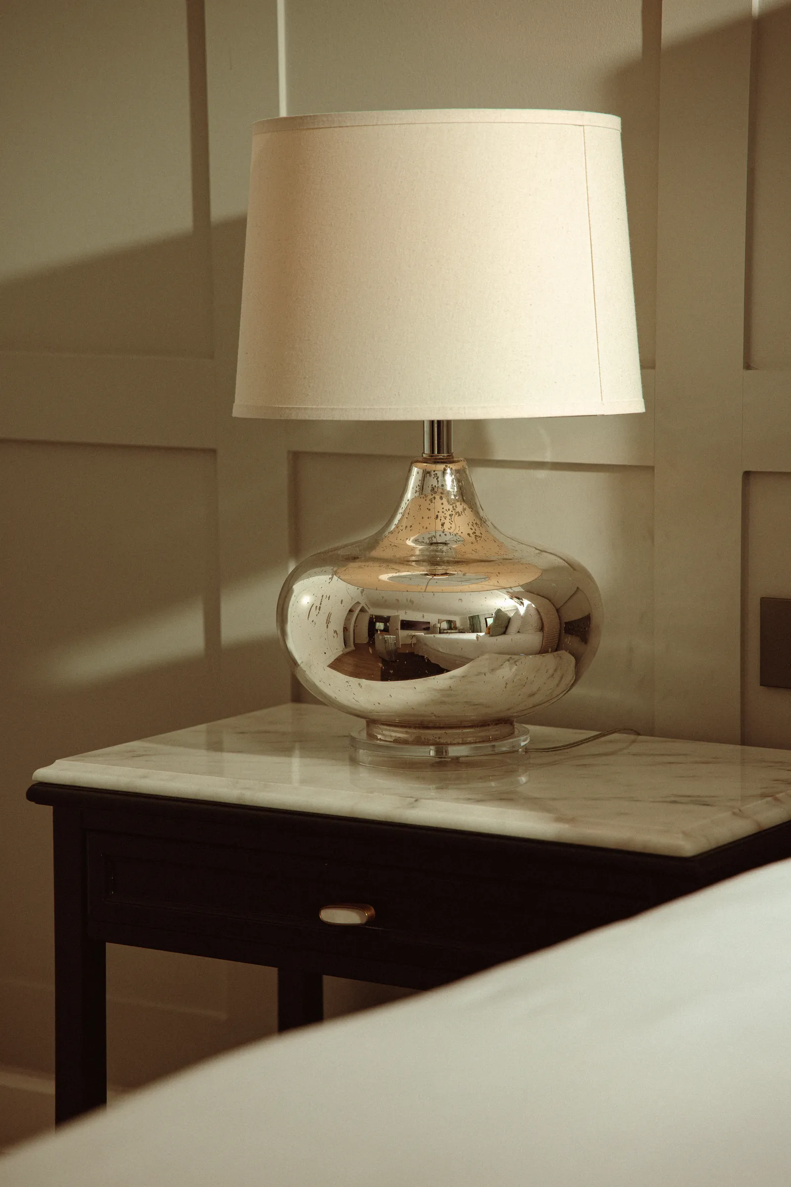 Silver table lamp on a marble bedside table