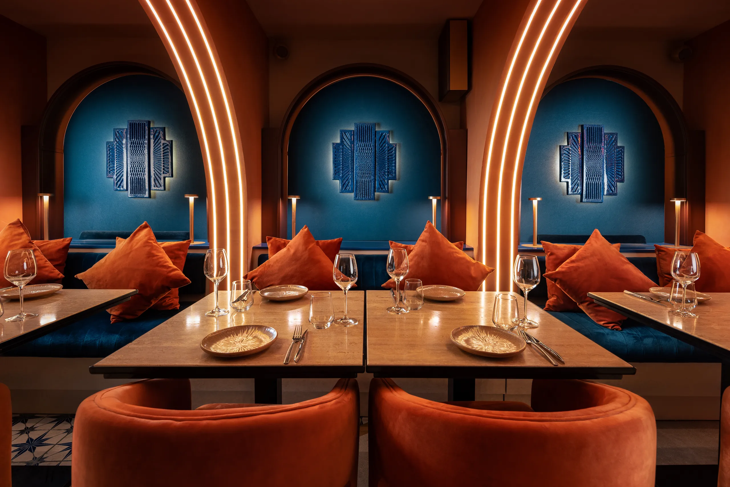 Dining booths with blue arched niches, orange cushions and set tables