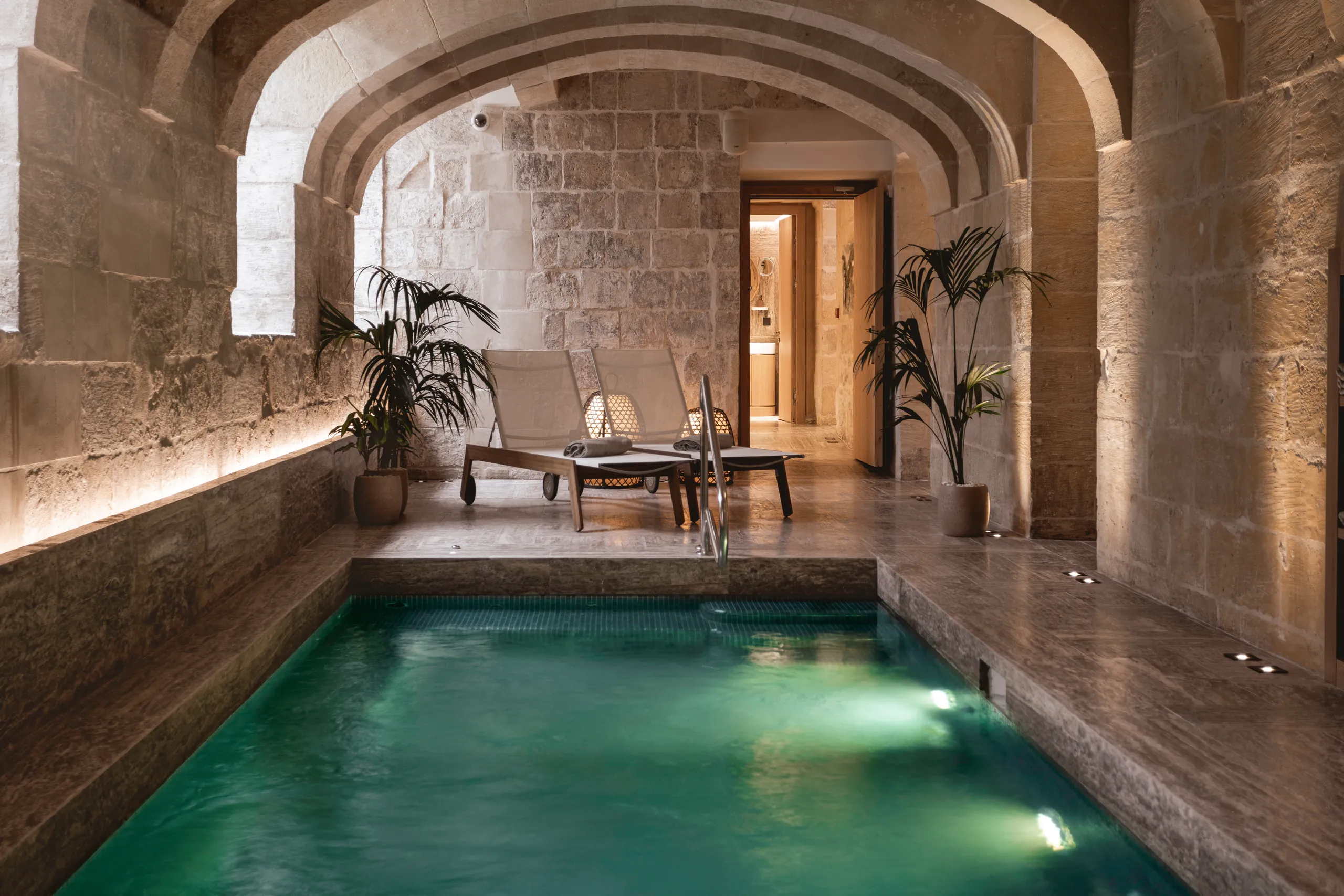 Spa pool with turquoise water in a vaulted limestone room