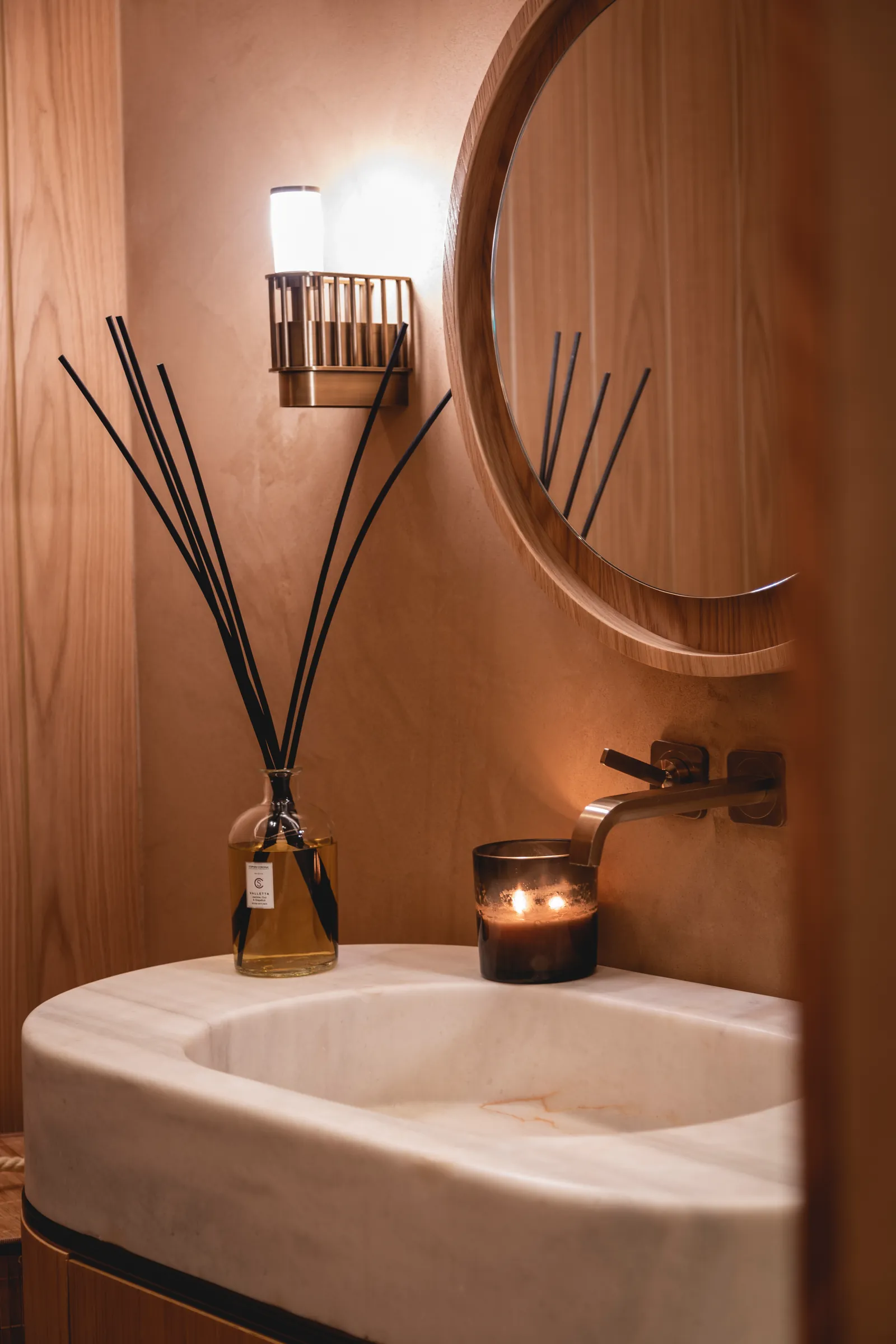 Spa basin with a round mirror, reed diffuser and candle
