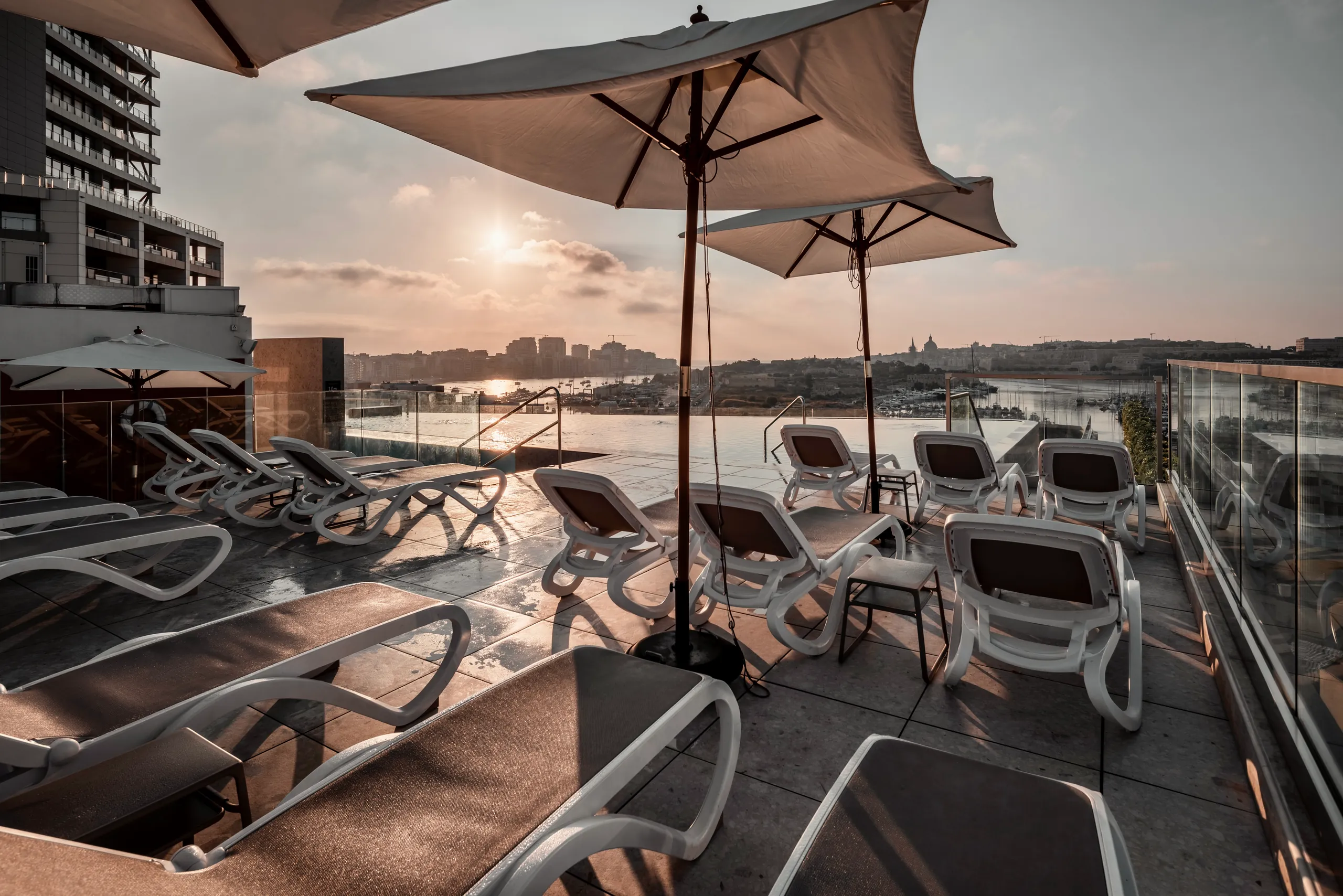 Terrace with sun loungers and parasols at sunset beside the harbour