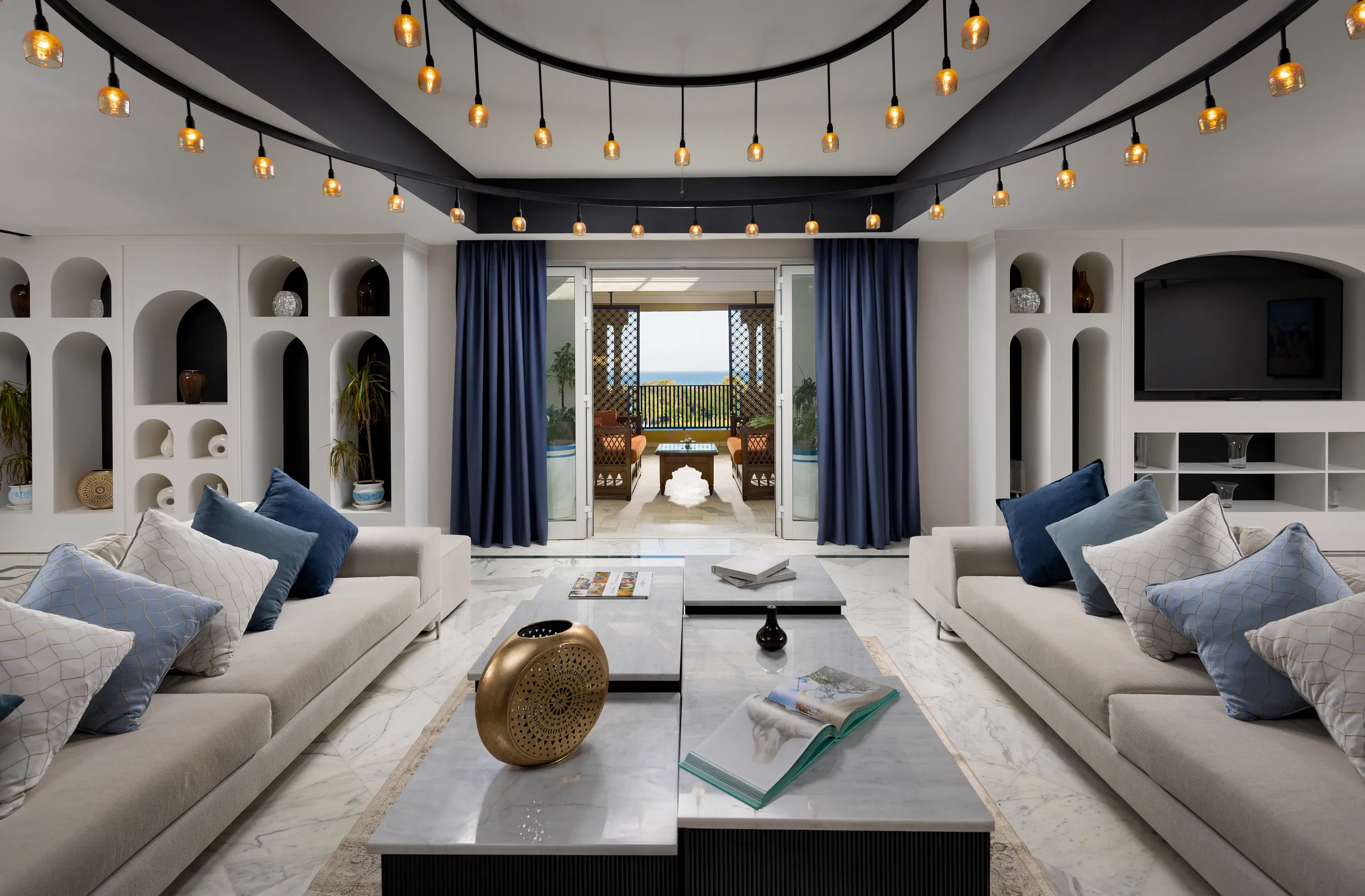 Living room with white arched shelving, navy curtains, sofas and a gold sculpture on the table