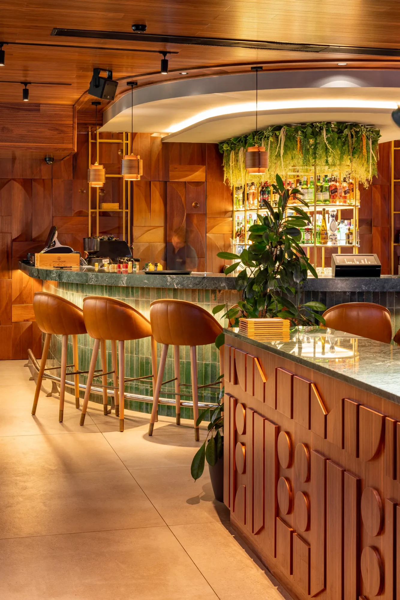 Bar counter with green stools and hanging plants