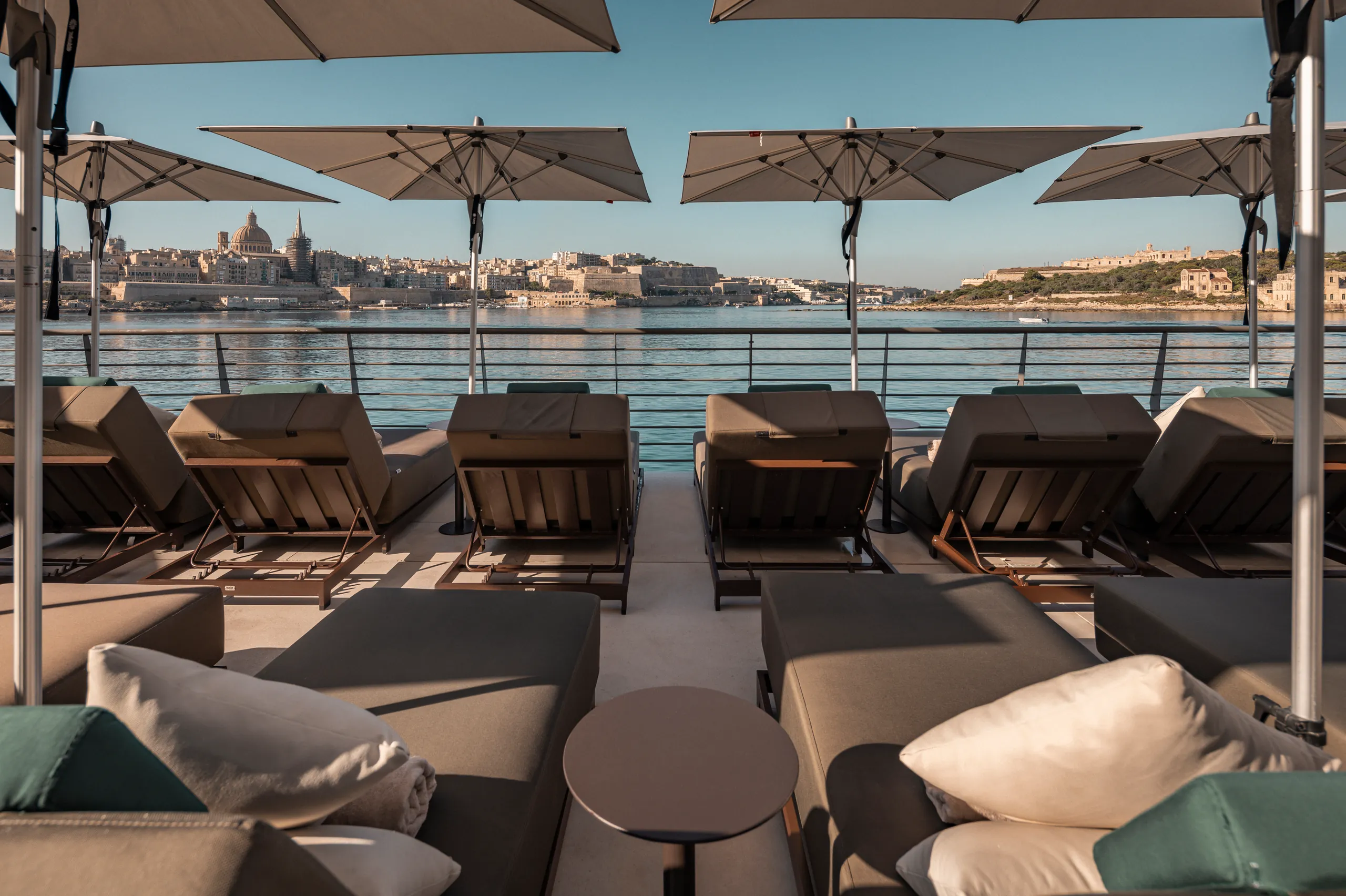 Rooftop terrace with loungers and parasols overlooking the harbour and city