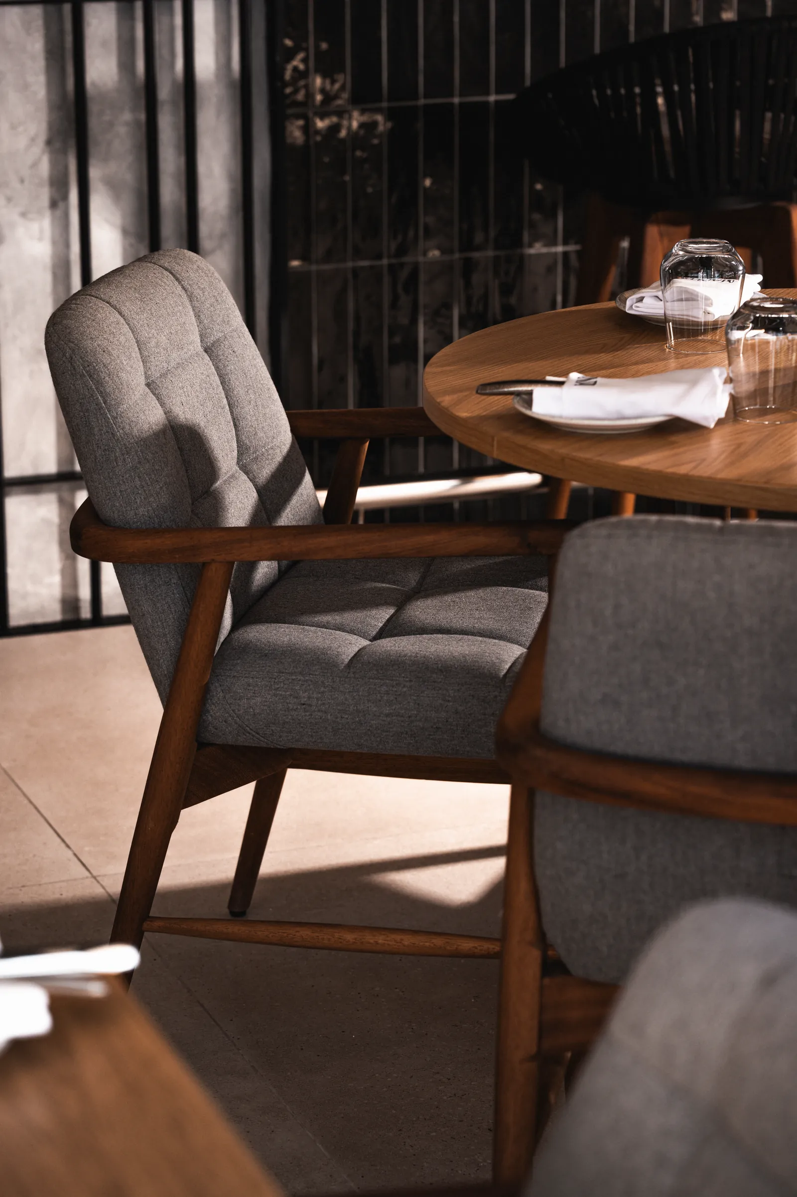 Corner of a dark dining room with a grey armchair and a round table