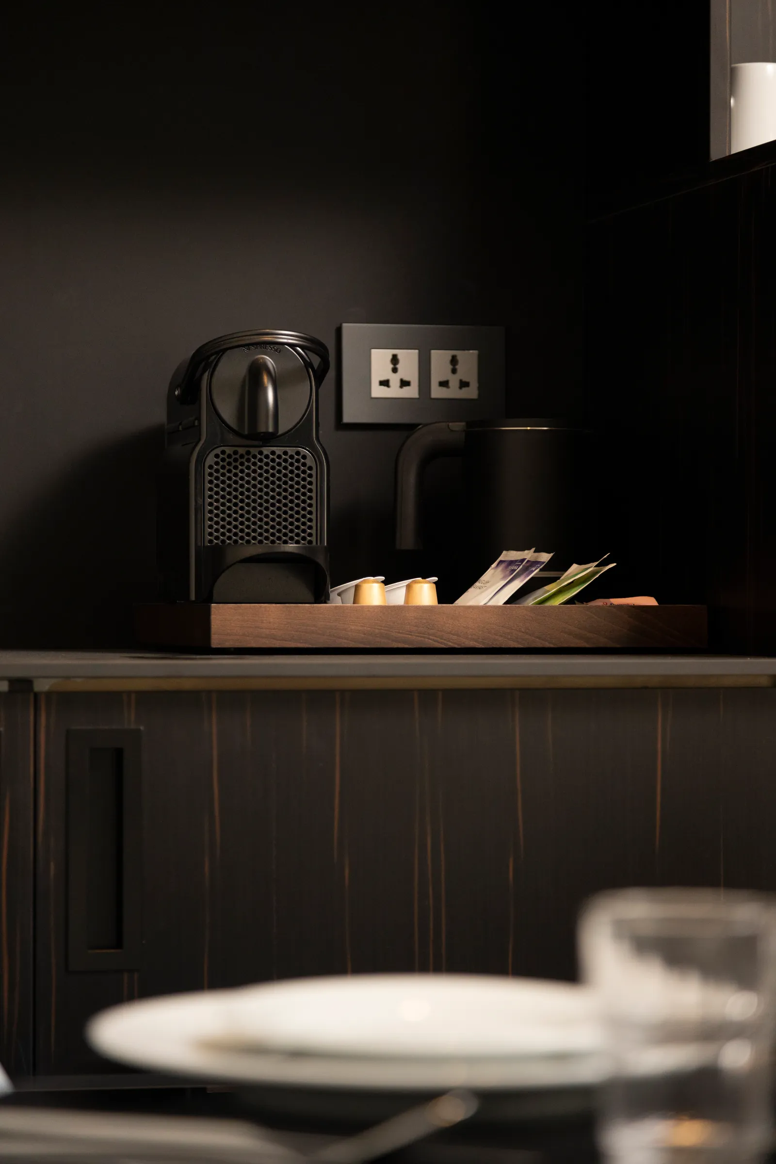 Dark minibar corner with a tray and glassware