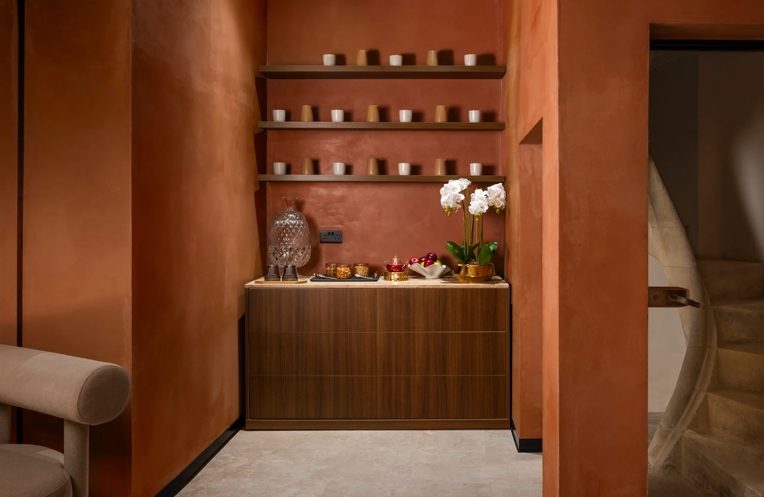 Spa refreshment counter with shelves of candles and an orchid against a terracotta wall
