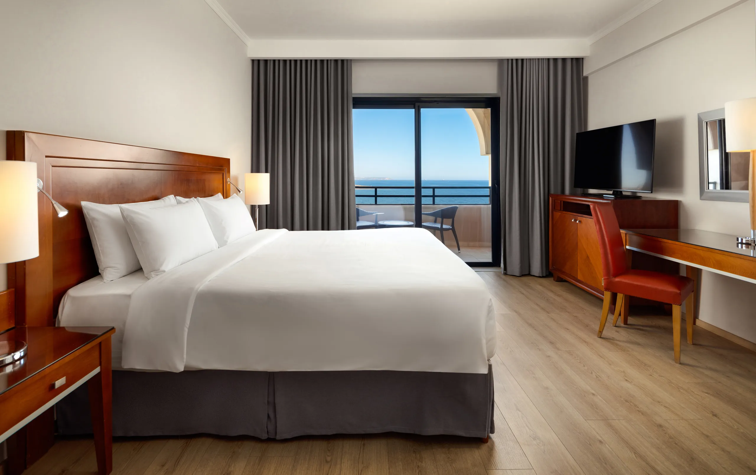 Sea-view hotel guest room with a double bed and balcony doors