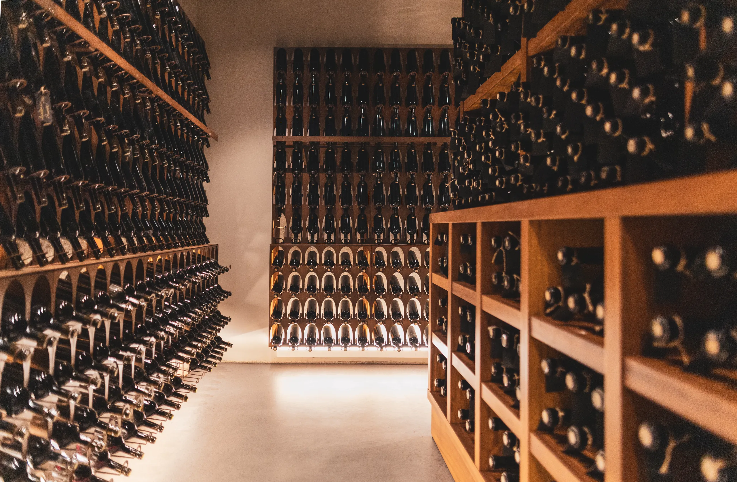Wine cellar with floor-to-ceiling racks of bottles and timber shelving