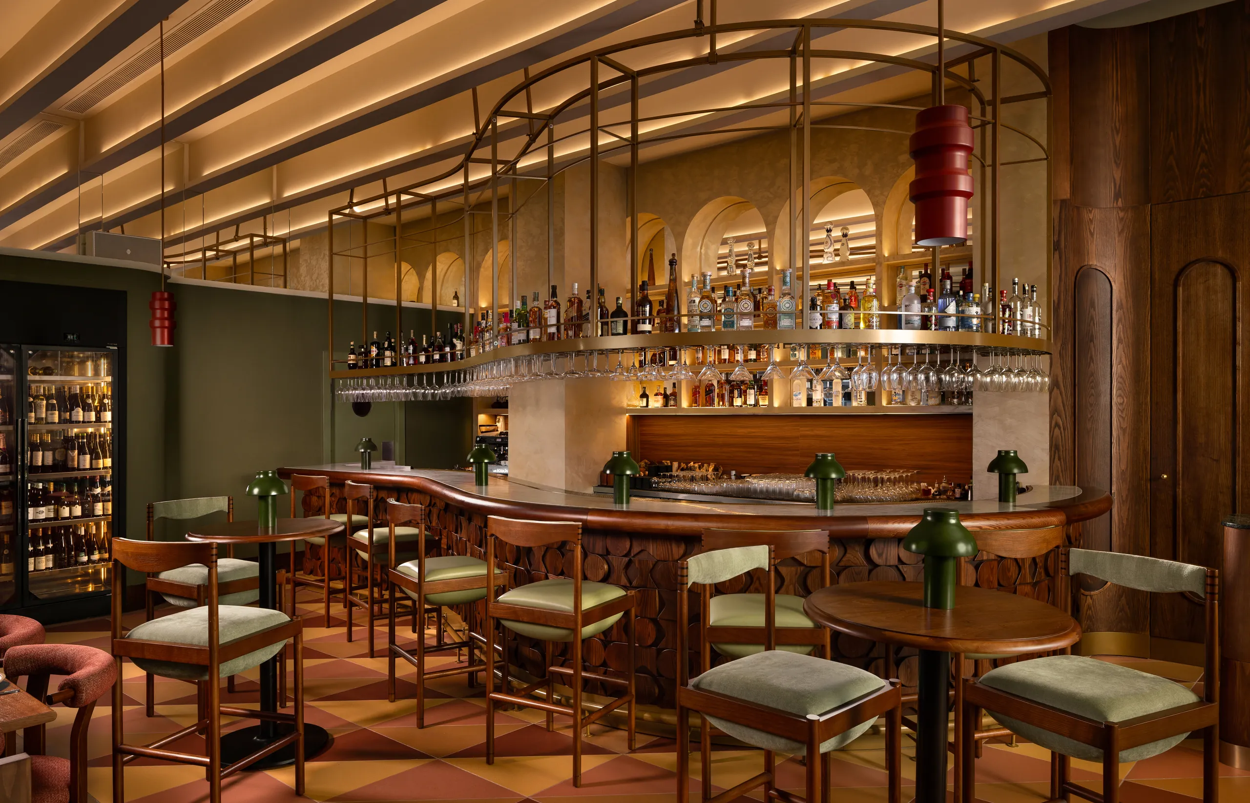 Curved bar counter with green leather chairs and backlit bottle shelves at Tanvi