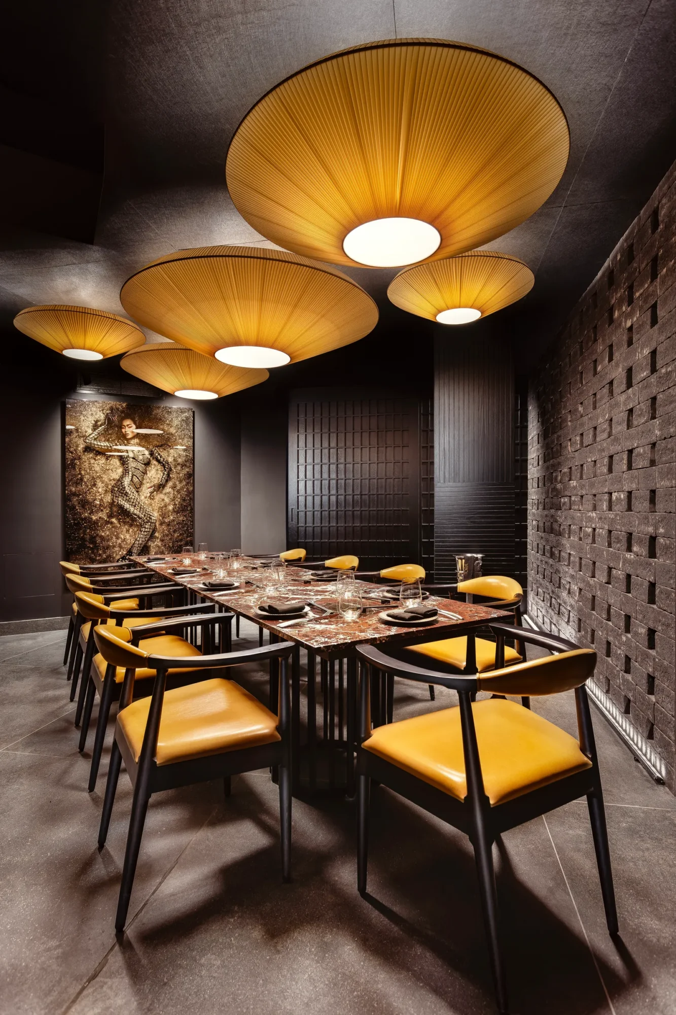 Tables with mustard-yellow chairs under woven pendant lamps at Tora