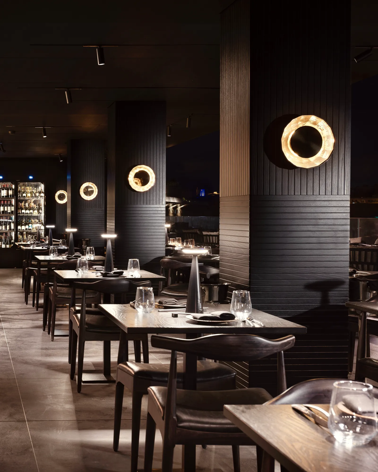 Set tables and black columns with round wall lights in the Tora dining room