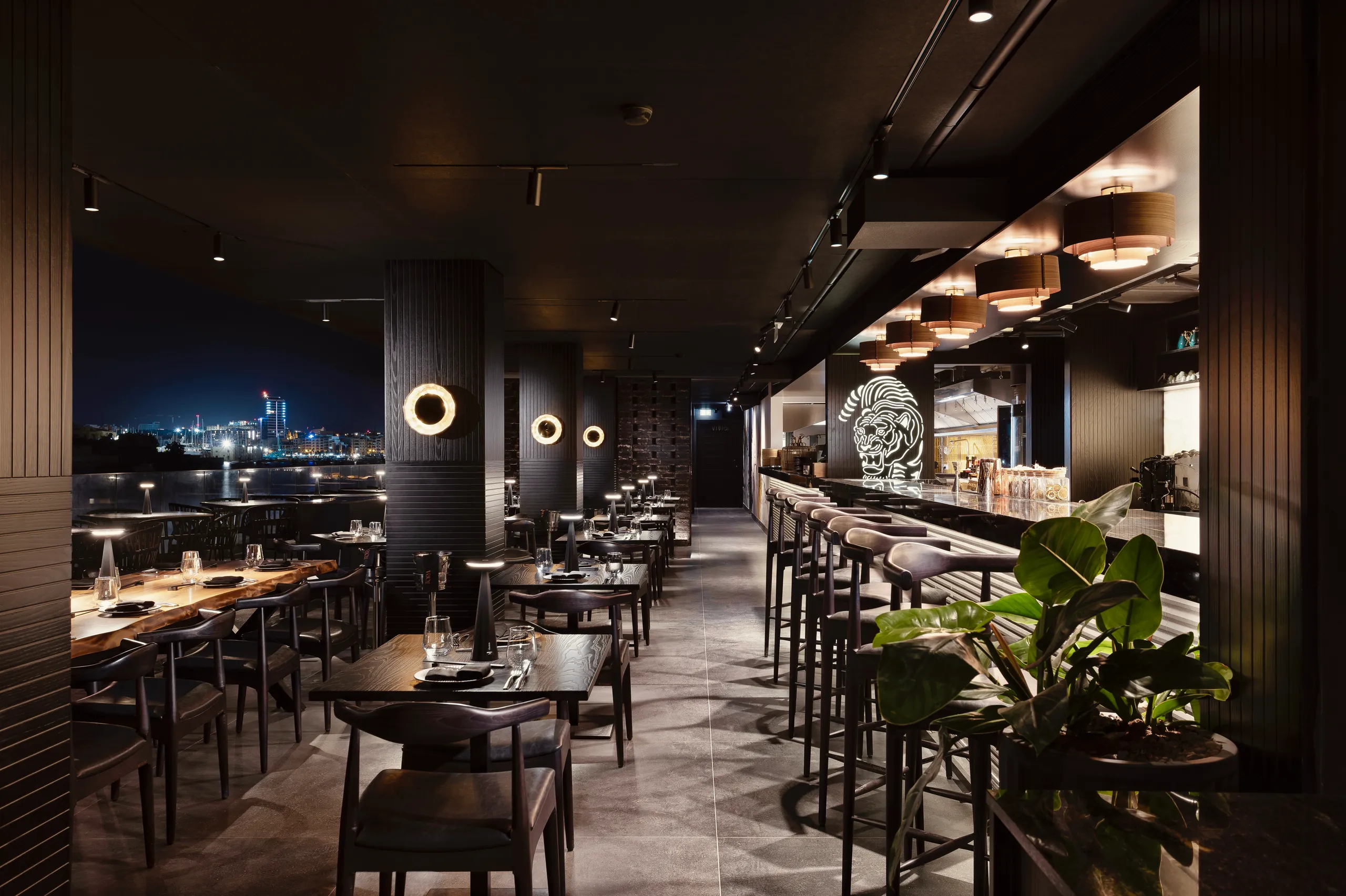 Dining room with the bar on the right and the night-time harbour through the windows