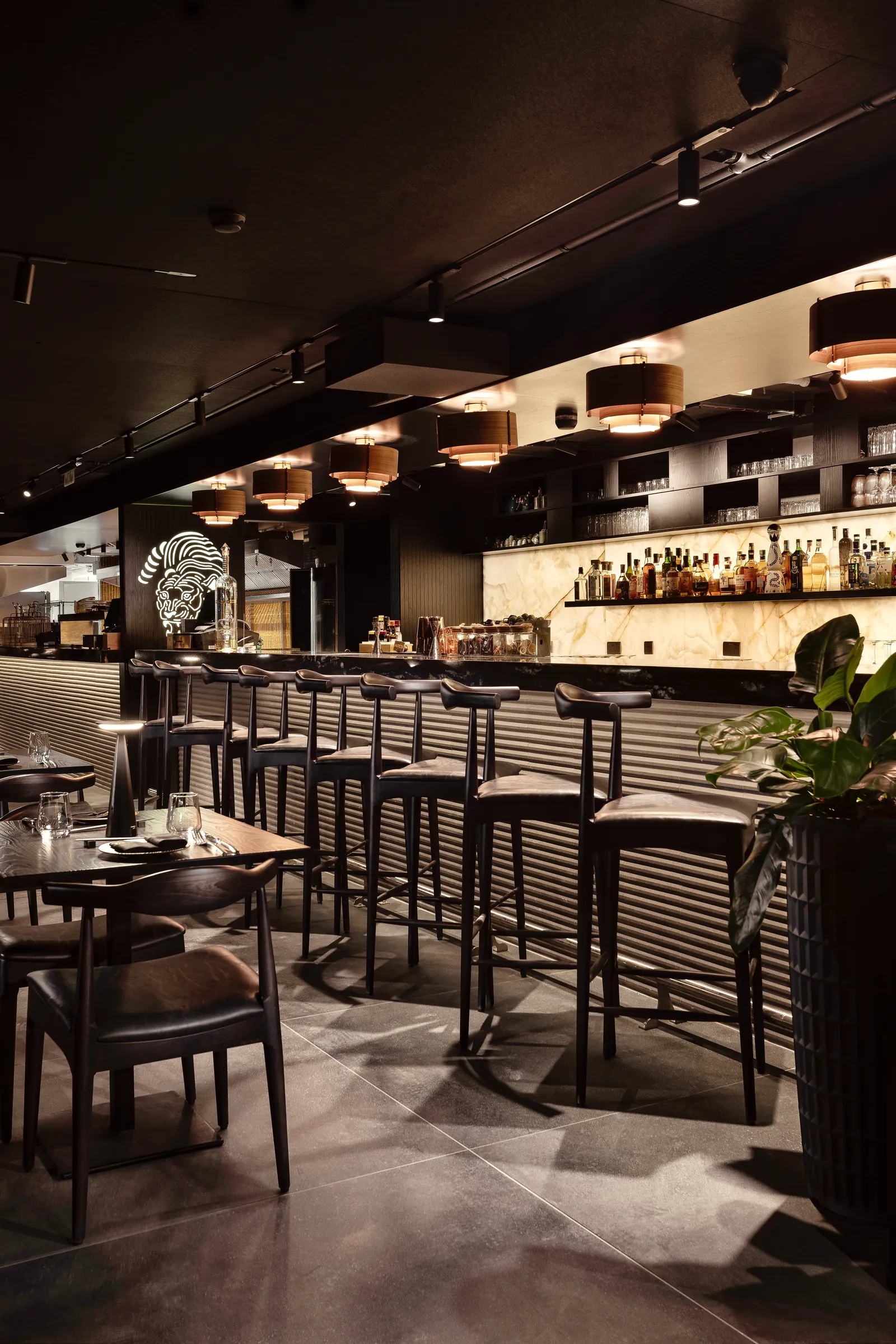 Bar stools and tables in front of the lit back bar at Tora
