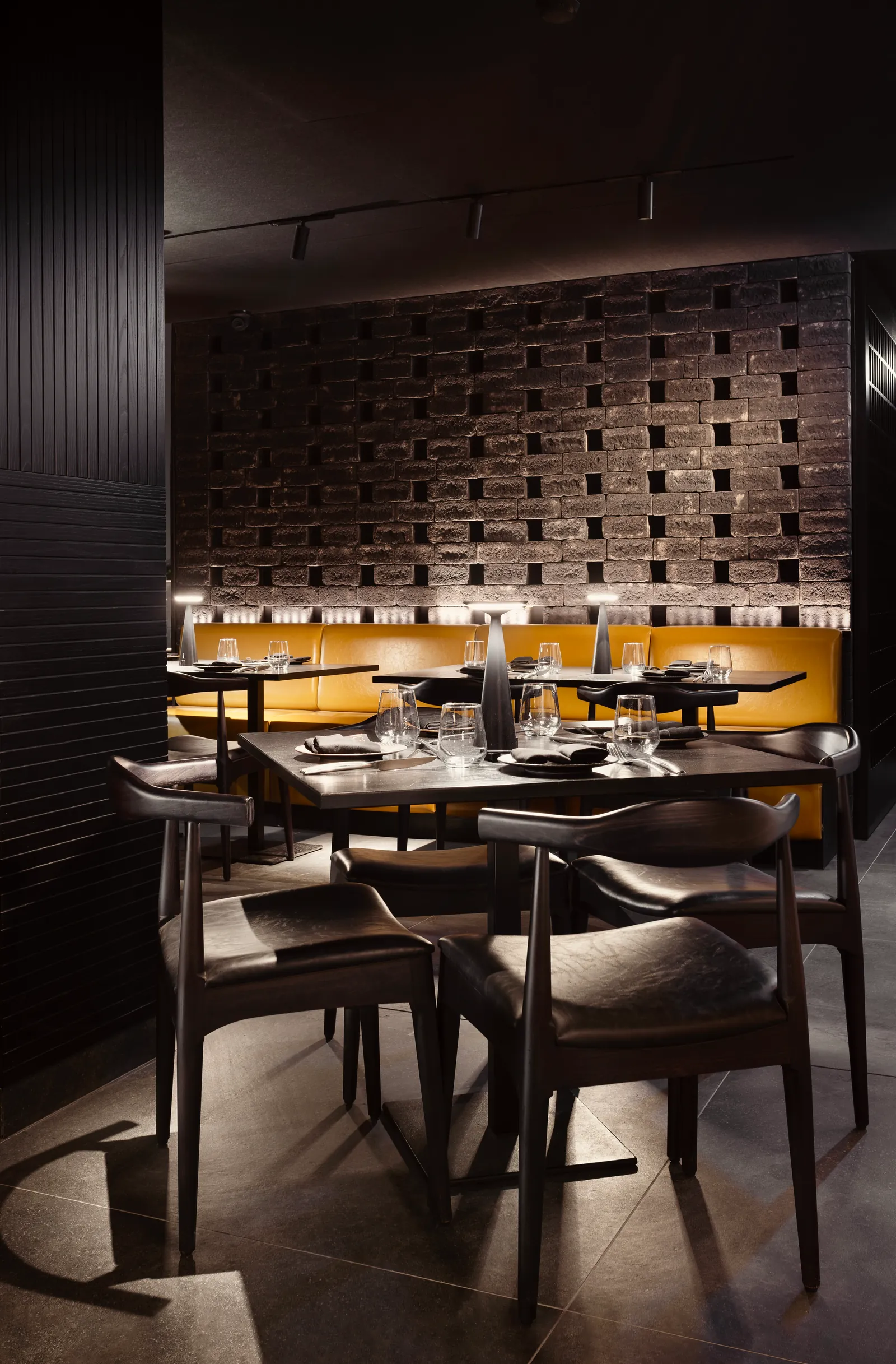 Corner of the Tora dining room with a patterned brick wall and mustard chairs