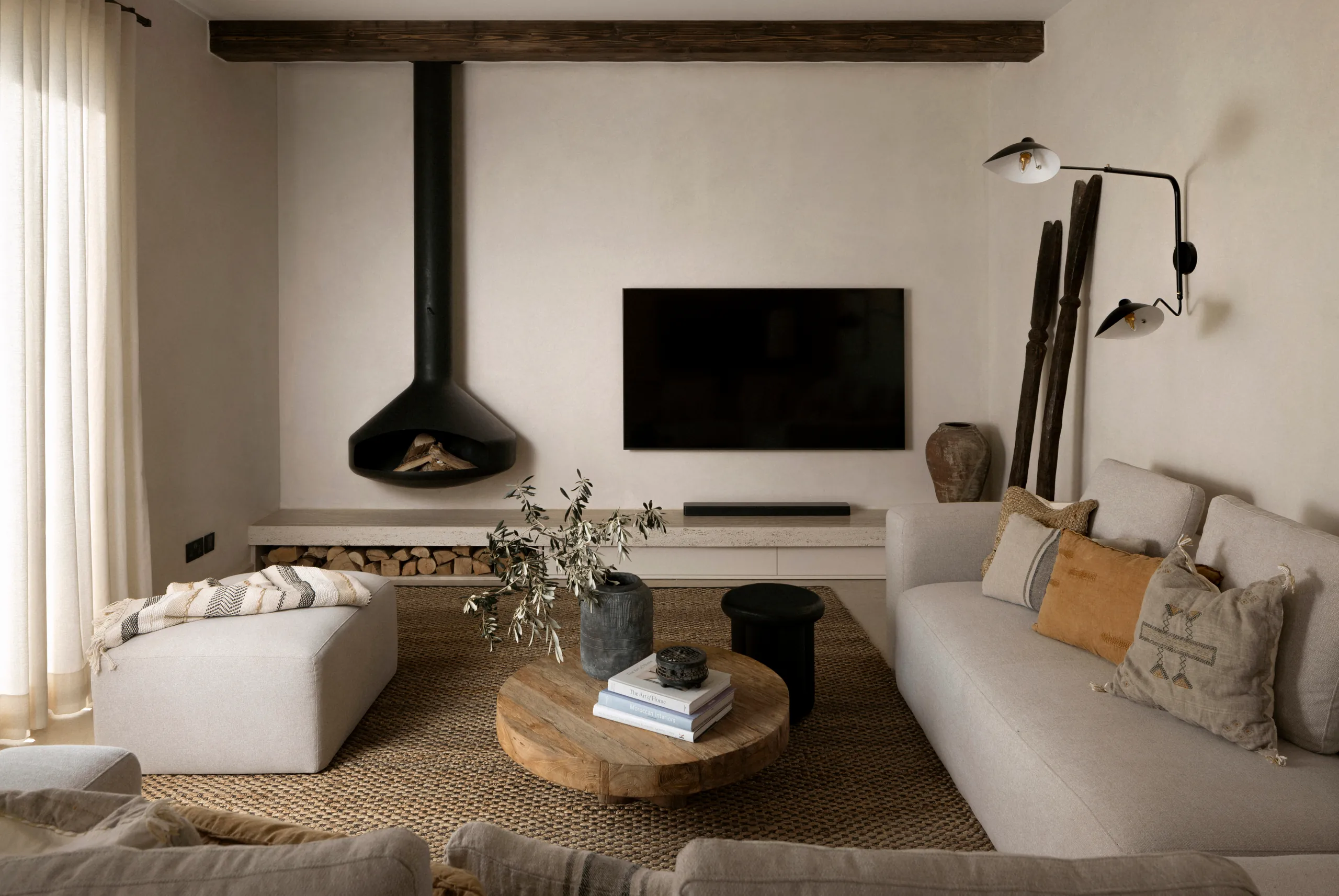 Living room with a black suspended fireplace, cream sofa and round wooden coffee table