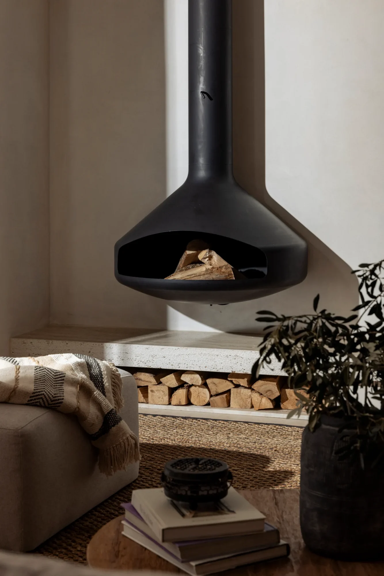 Black suspended fireplace in a living room with stacked logs