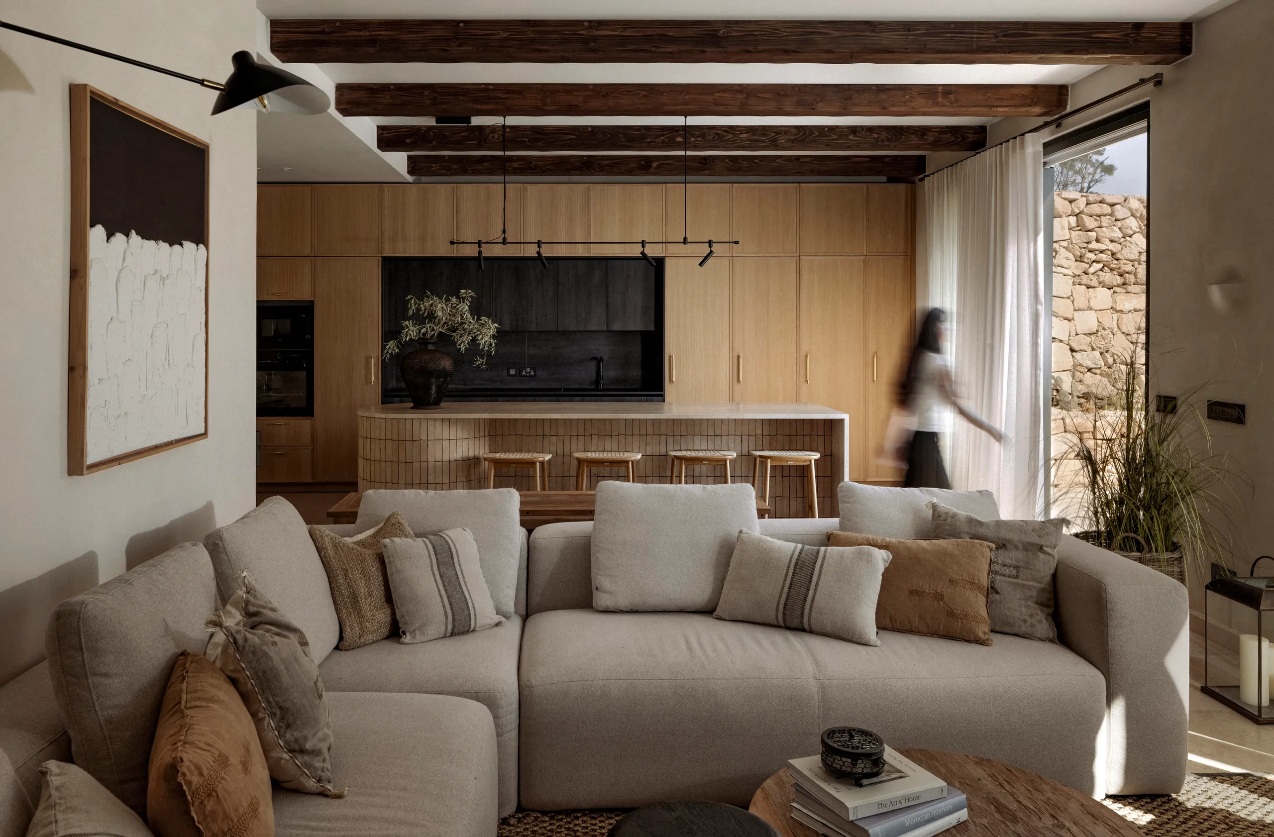 Open-plan living room with a cream sofa and oak kitchen, with a stone wall beyond