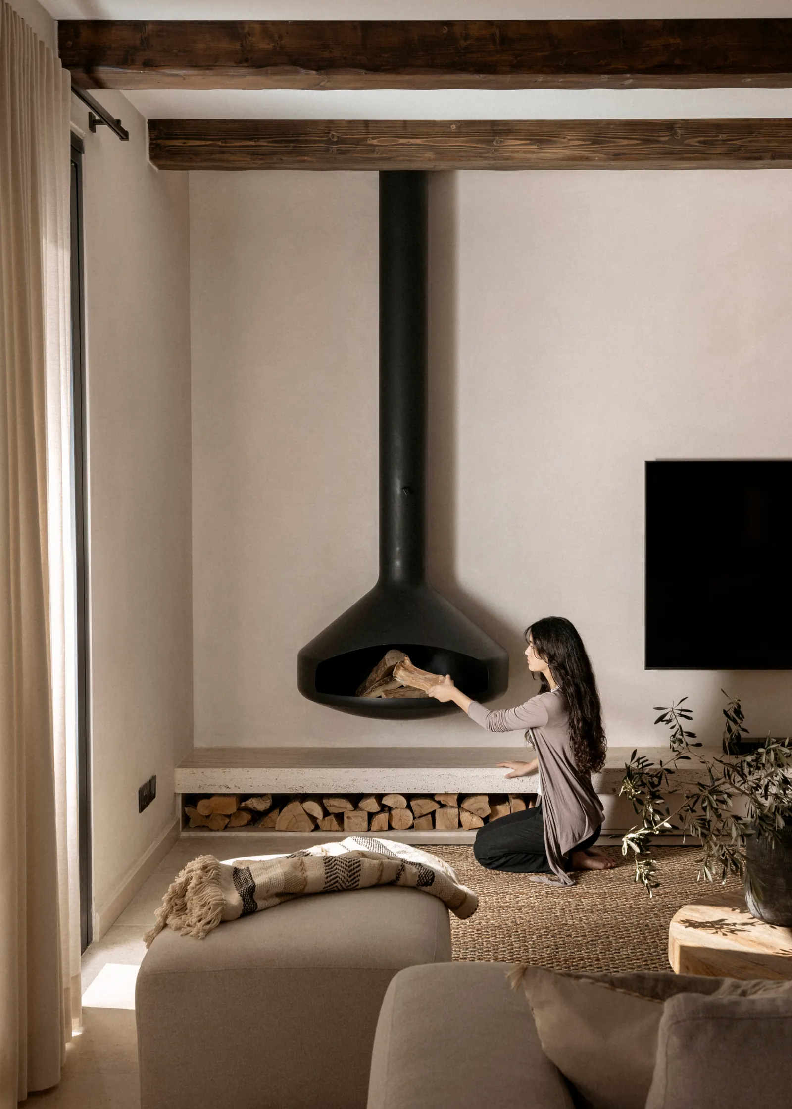 Side view of the living room fireplace and wall-mounted TV under dark ceiling beams