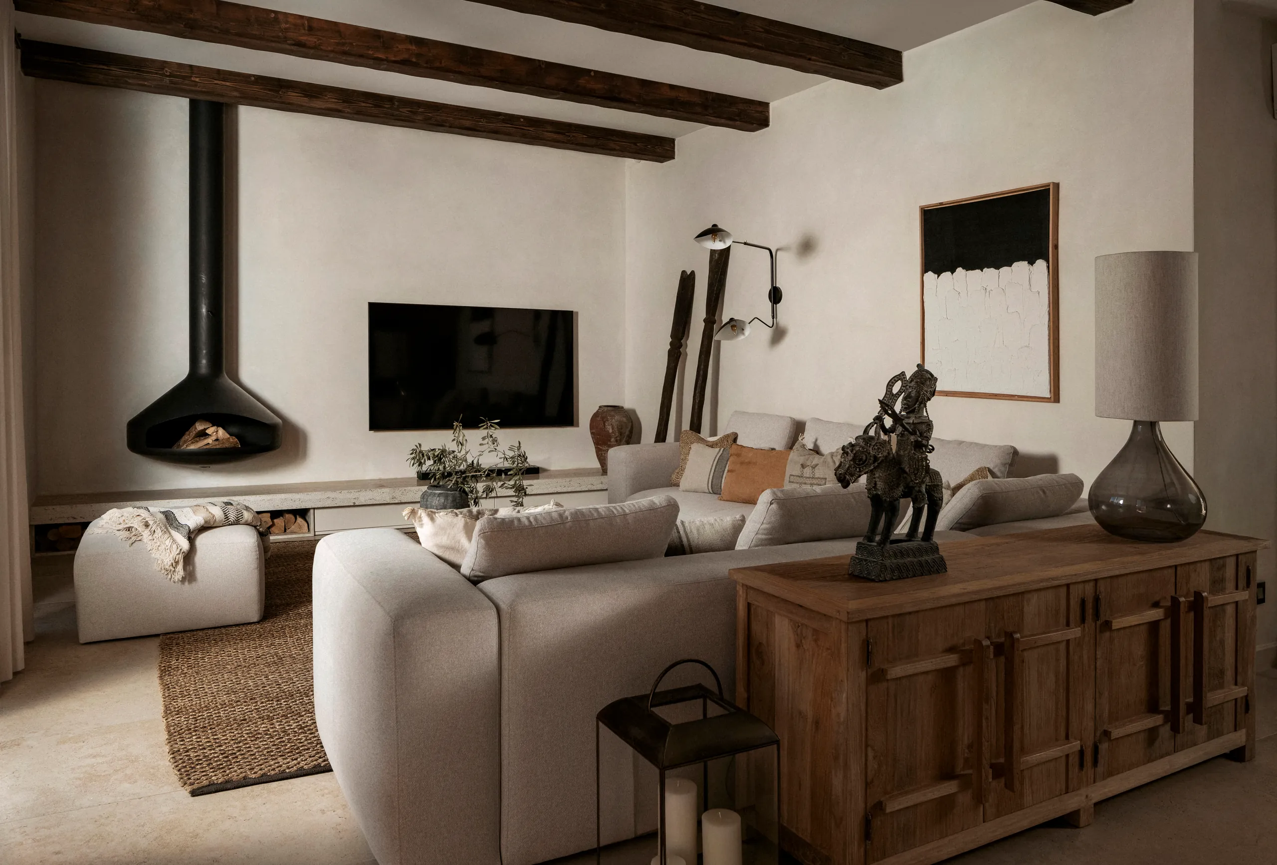Beamed living room with a corner sofa, timber sideboard and pale abstract painting