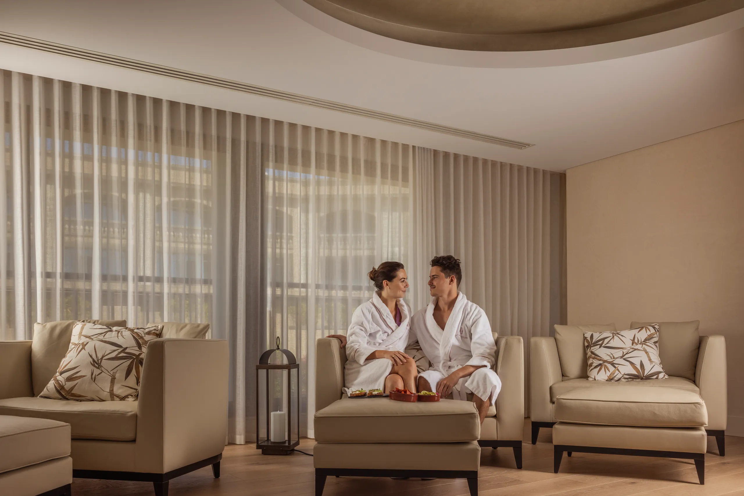 Couple in white robes relaxing on sofas in a spa lounge