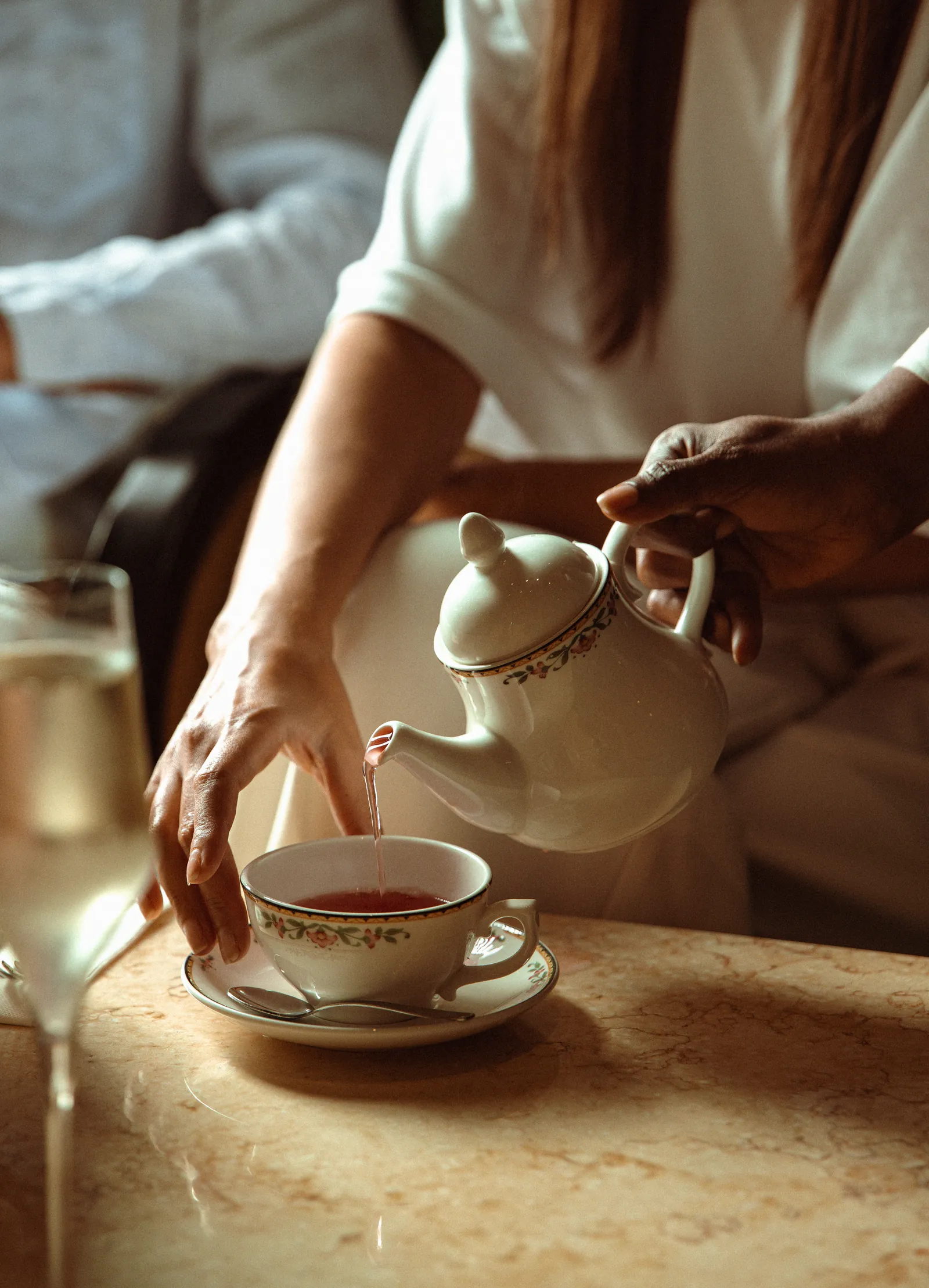 Server pouring tea into a cup at a laid table