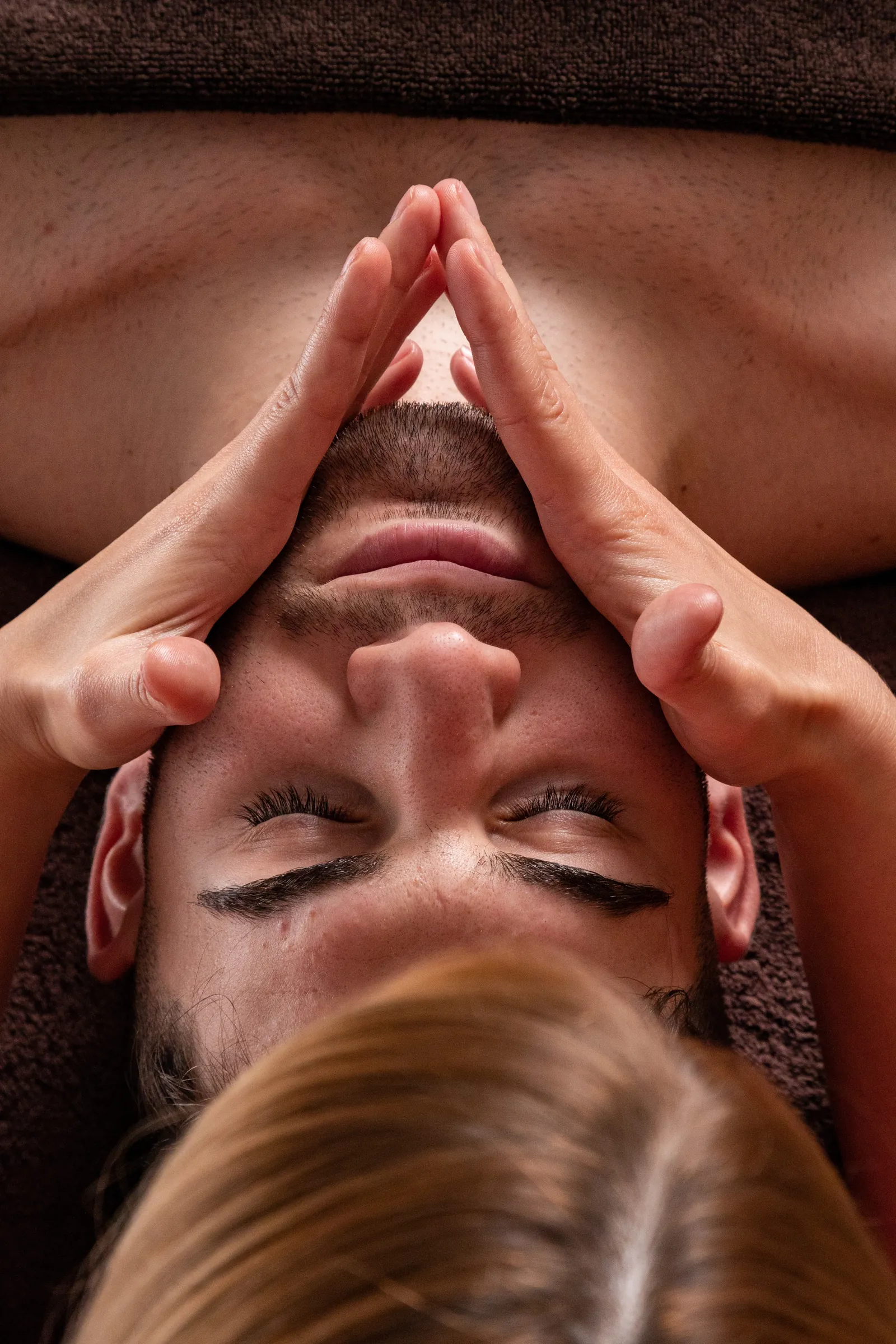 Spa therapist's hands massaging a client's forehead