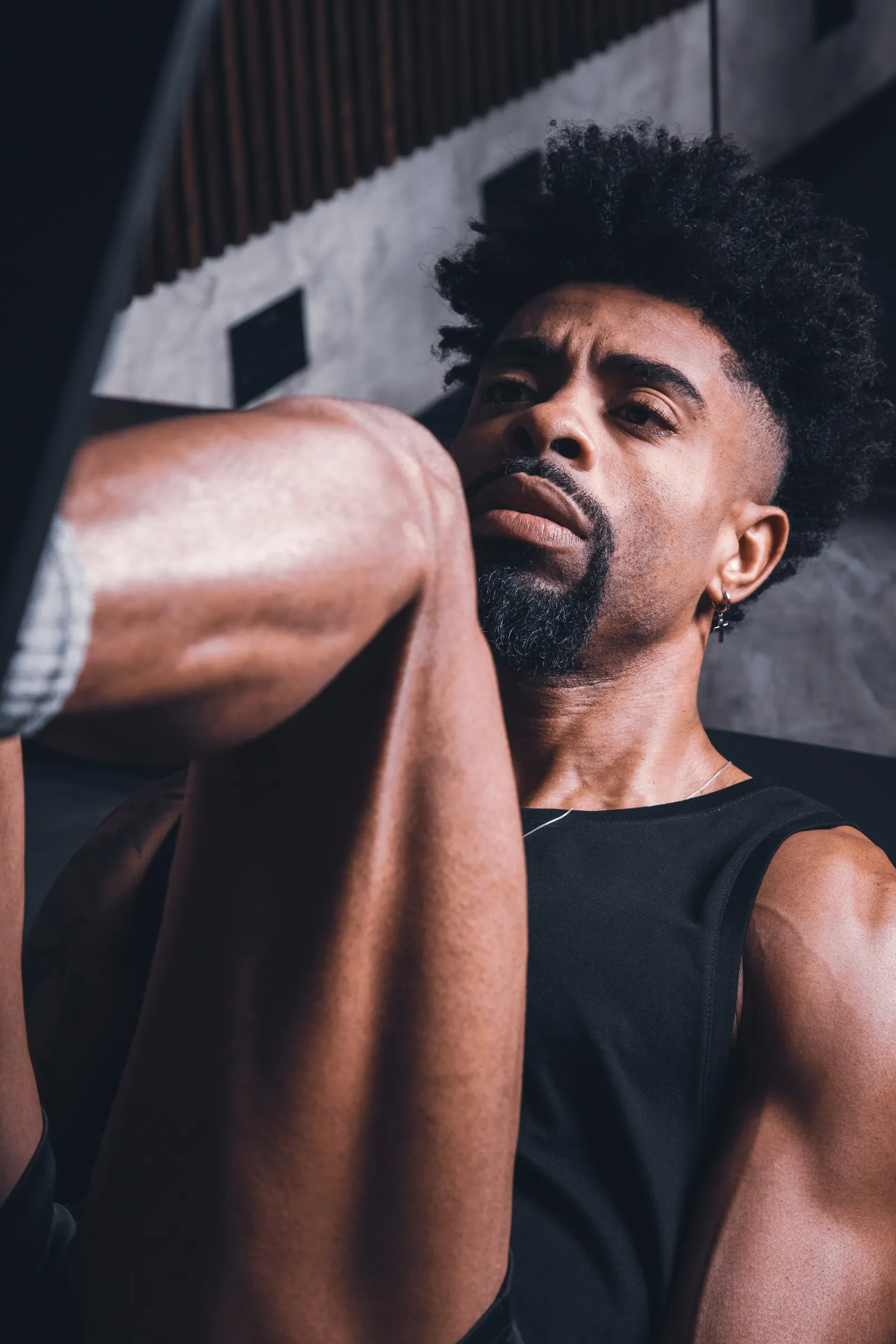 Man in a black vest crouching in a dark gym