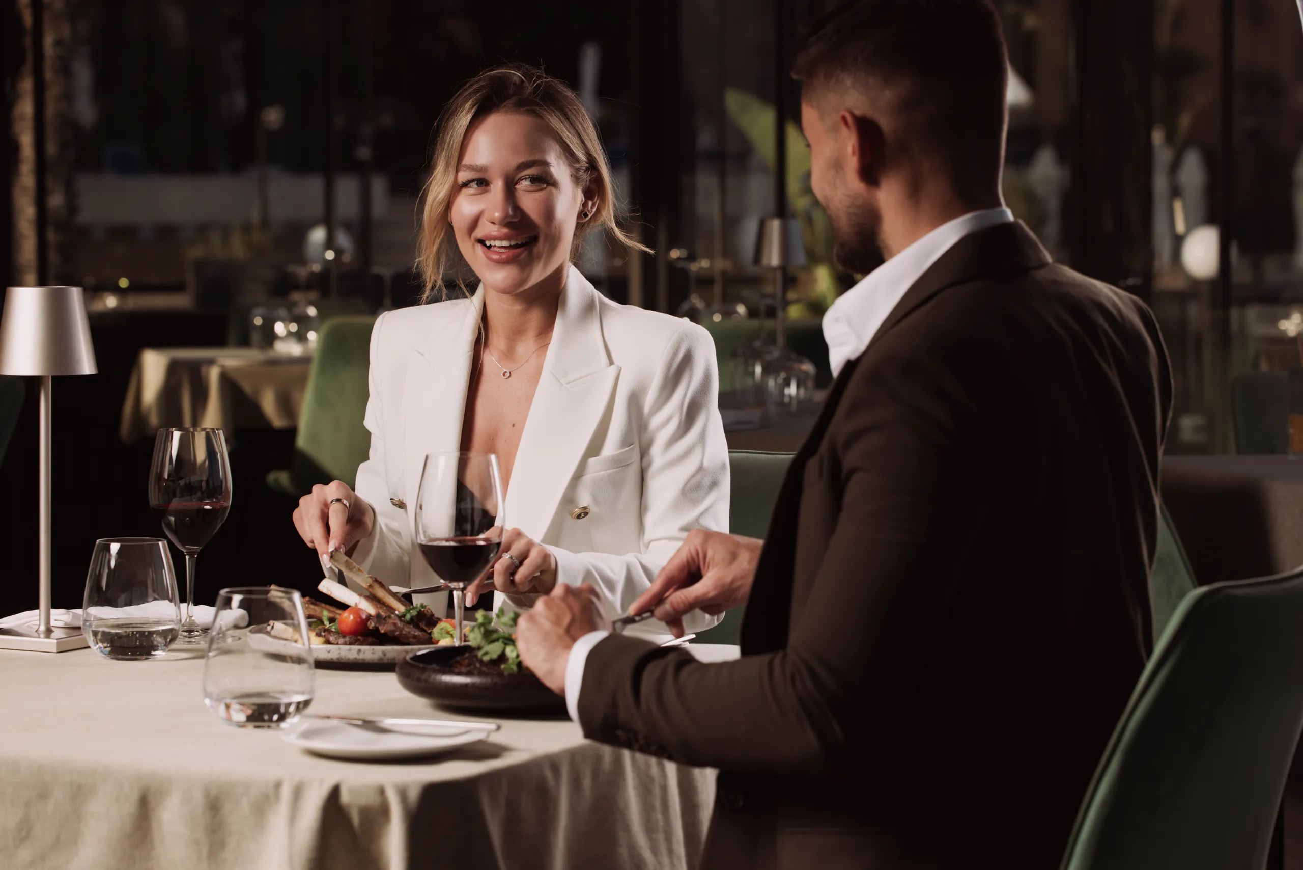 Smiling couple dining at a candlelit table with wine glasses
