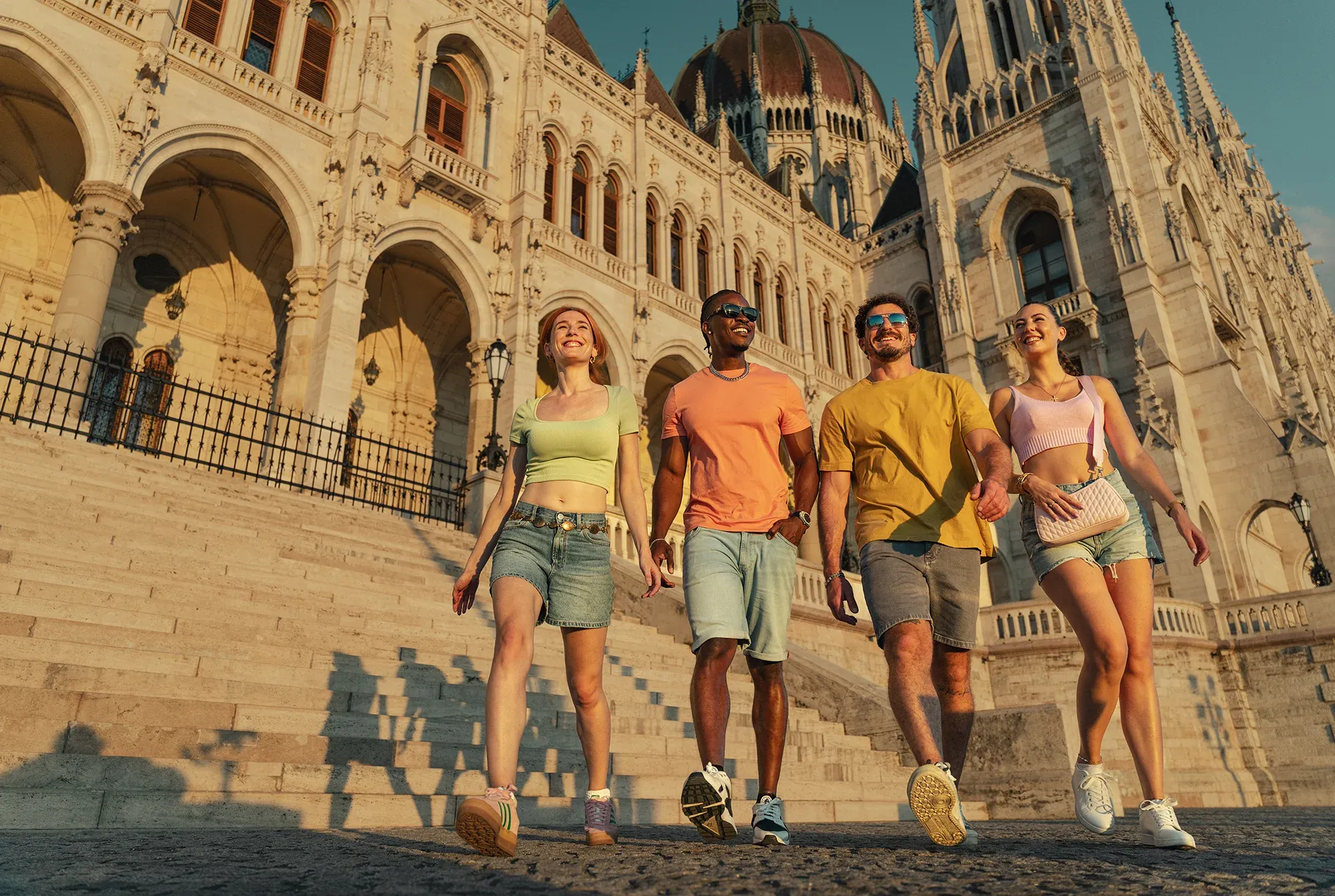 Four friends walking down the steps of the Hungarian Parliament Building in Budapest
