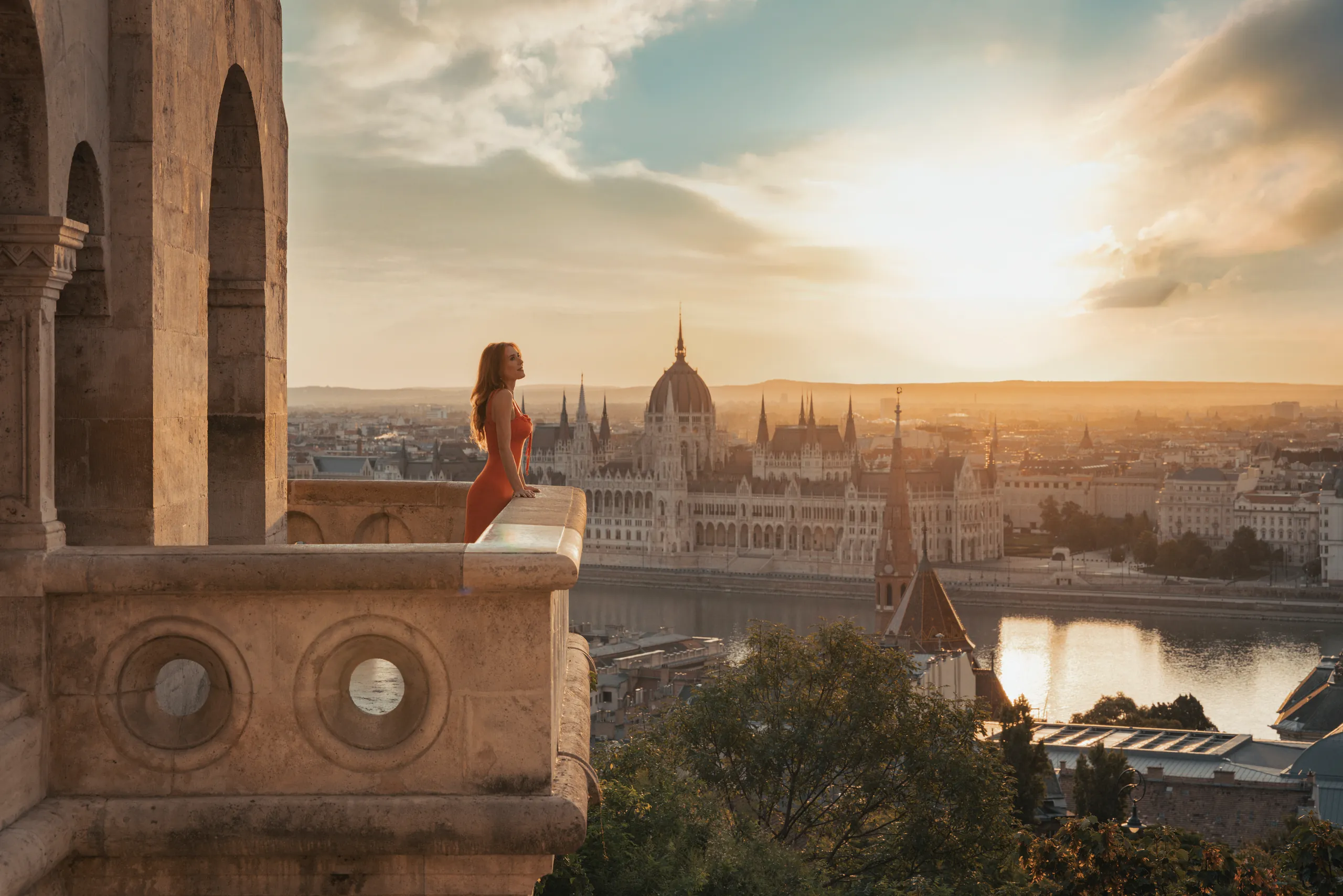 Woman looking over Budapest and the Danube at sunset, with the Hungarian Parliament Building in view