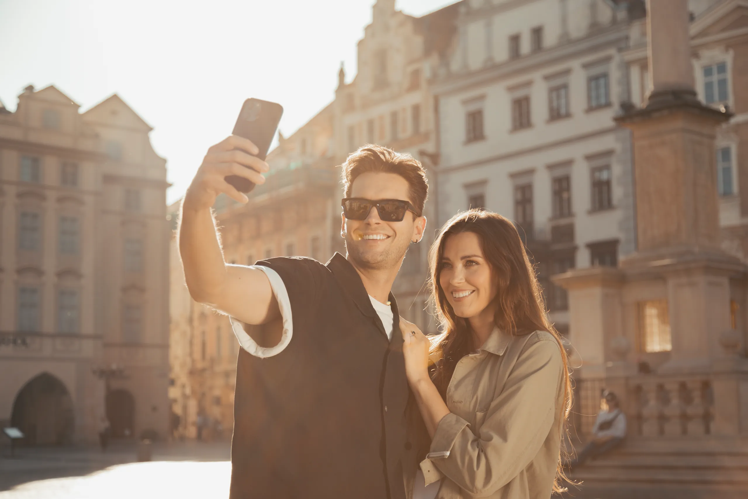 Man taking a selfie with a woman in the old town of Prague in morning light